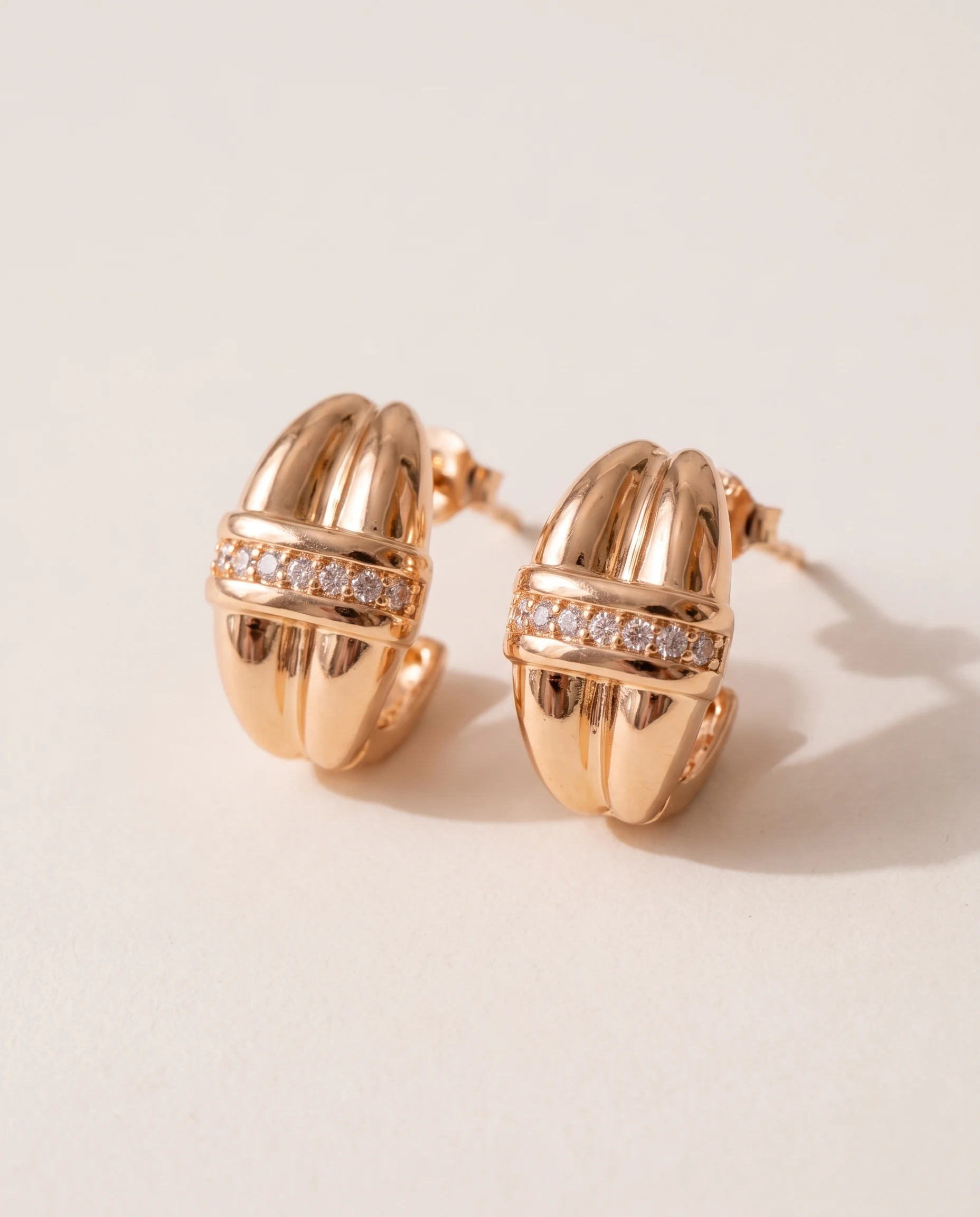 Domed two-row earrings with zircon details, pair laid flat, close-up view