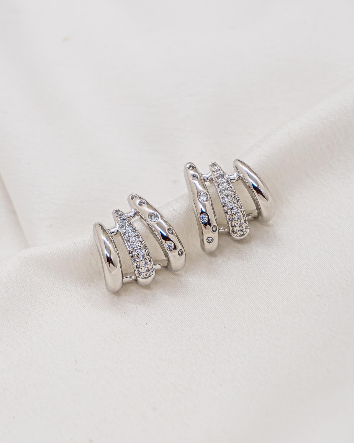 Boucles d’oreilles argentées à trois rangées, l’une lisse, l’autre pavée et la dernière ponctuée de pierres