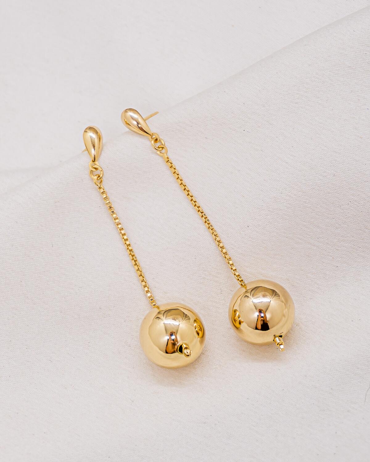 Paire de boucles d’oreilles dorées pendantes avec chaîne fine et grosse boule brillante
