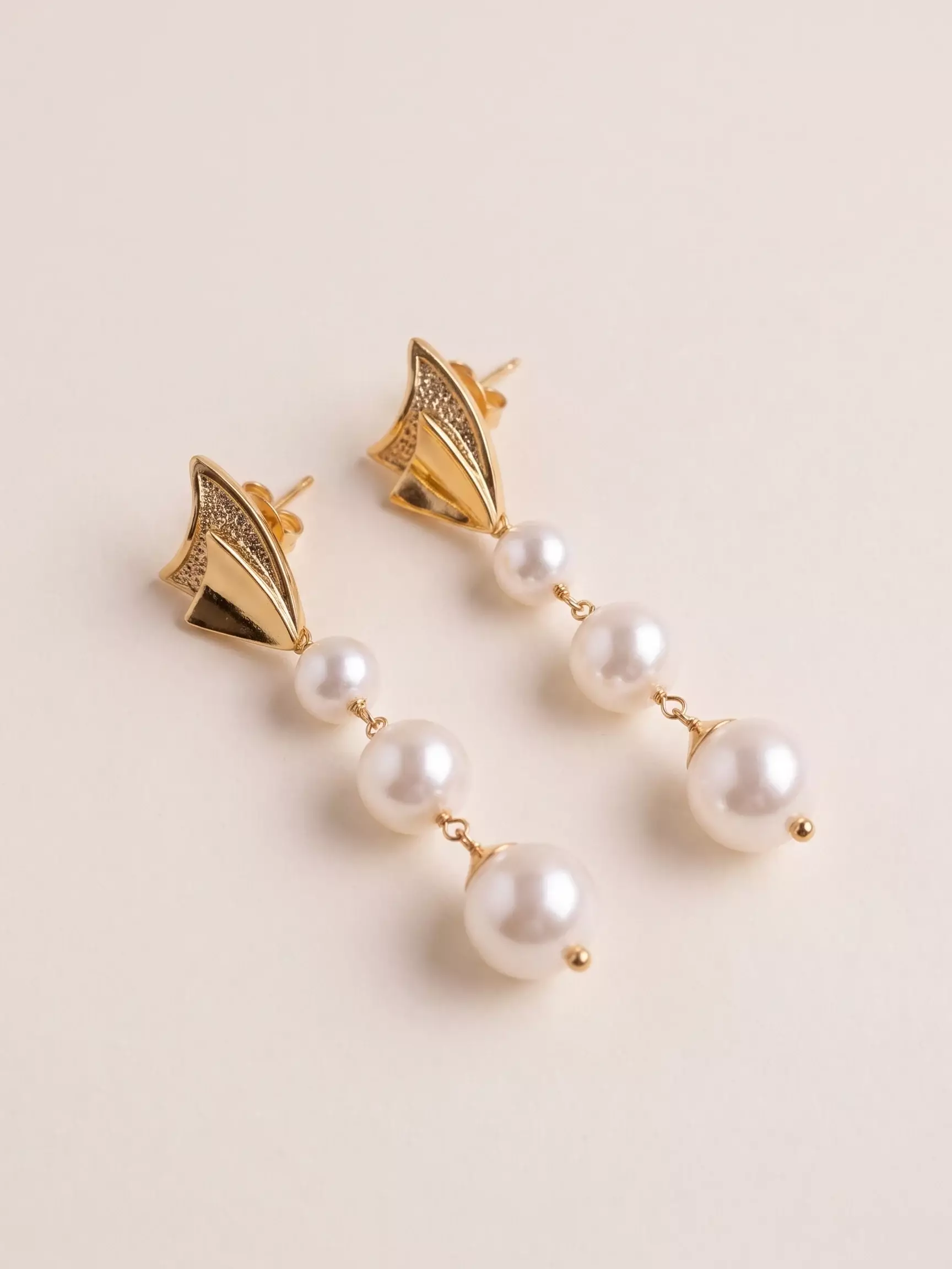Organic base earrings, 3 pearls, pair laid down, close-up view