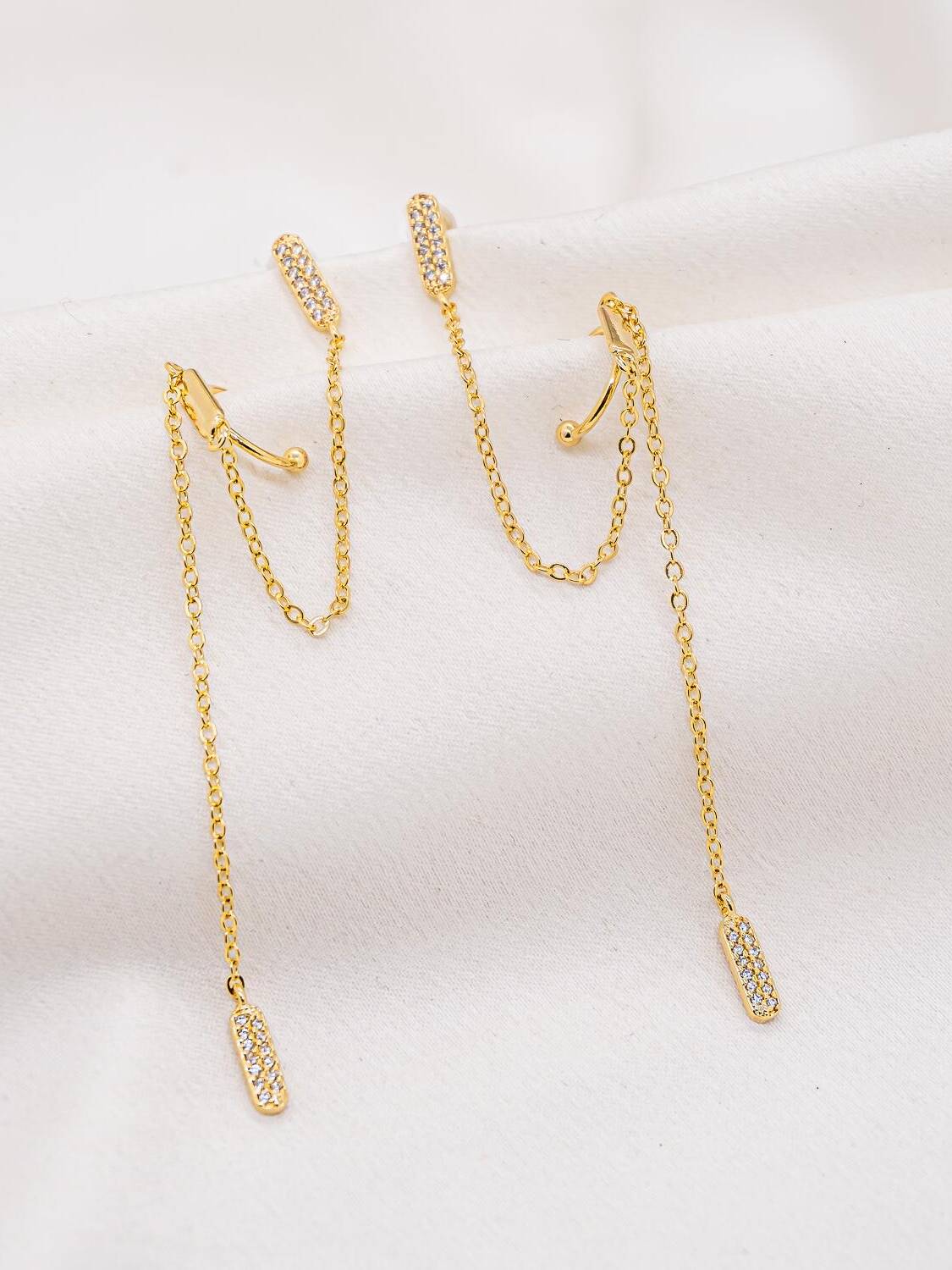 Paire de boucles d’oreilles dorées avec bâtonnets sertis, faux piercing et longue chaîne pendante