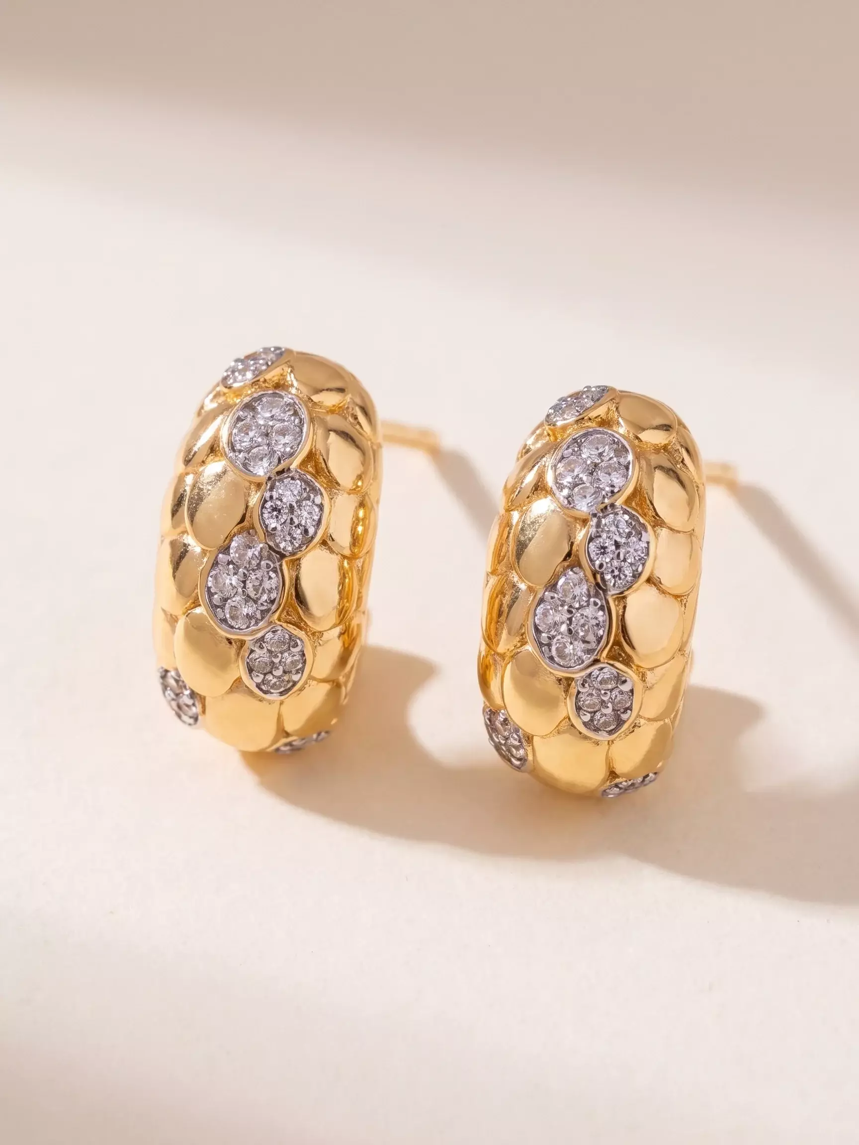 Boucles d'oreilles bombé écailles, détails sertis, la paire posée, vue de près