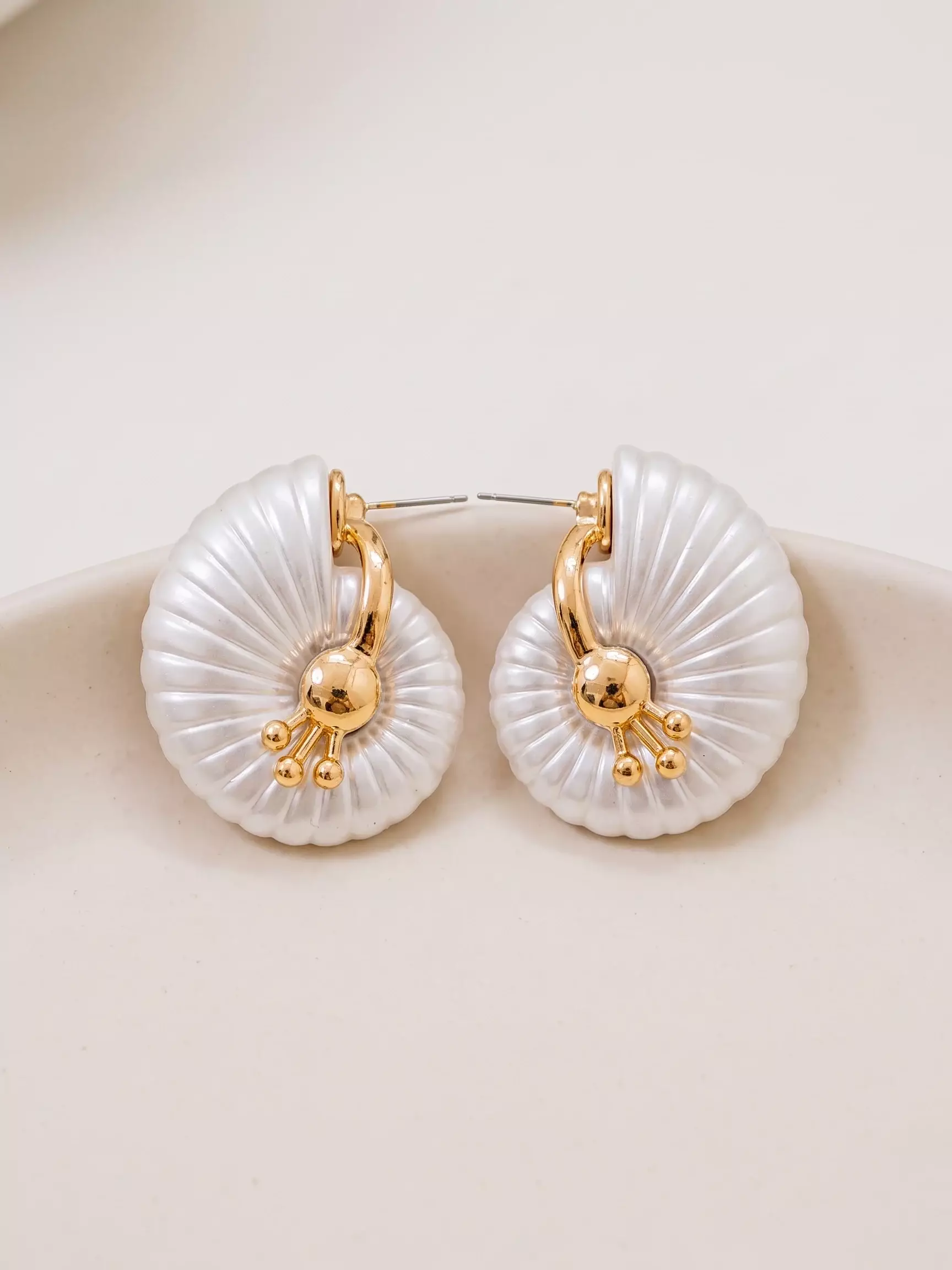 Maxi pearl shell stud earrings, pair laid flat, close-up view