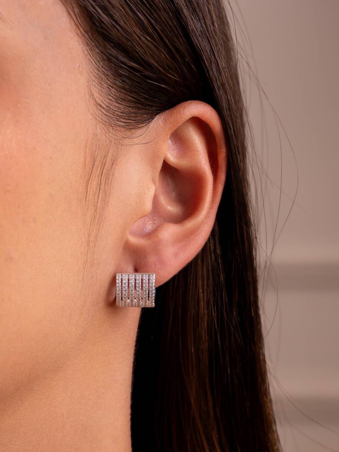 Boucles d’oreilles argentées à plusieurs rangées de petites pierres claires, portées à l’oreille