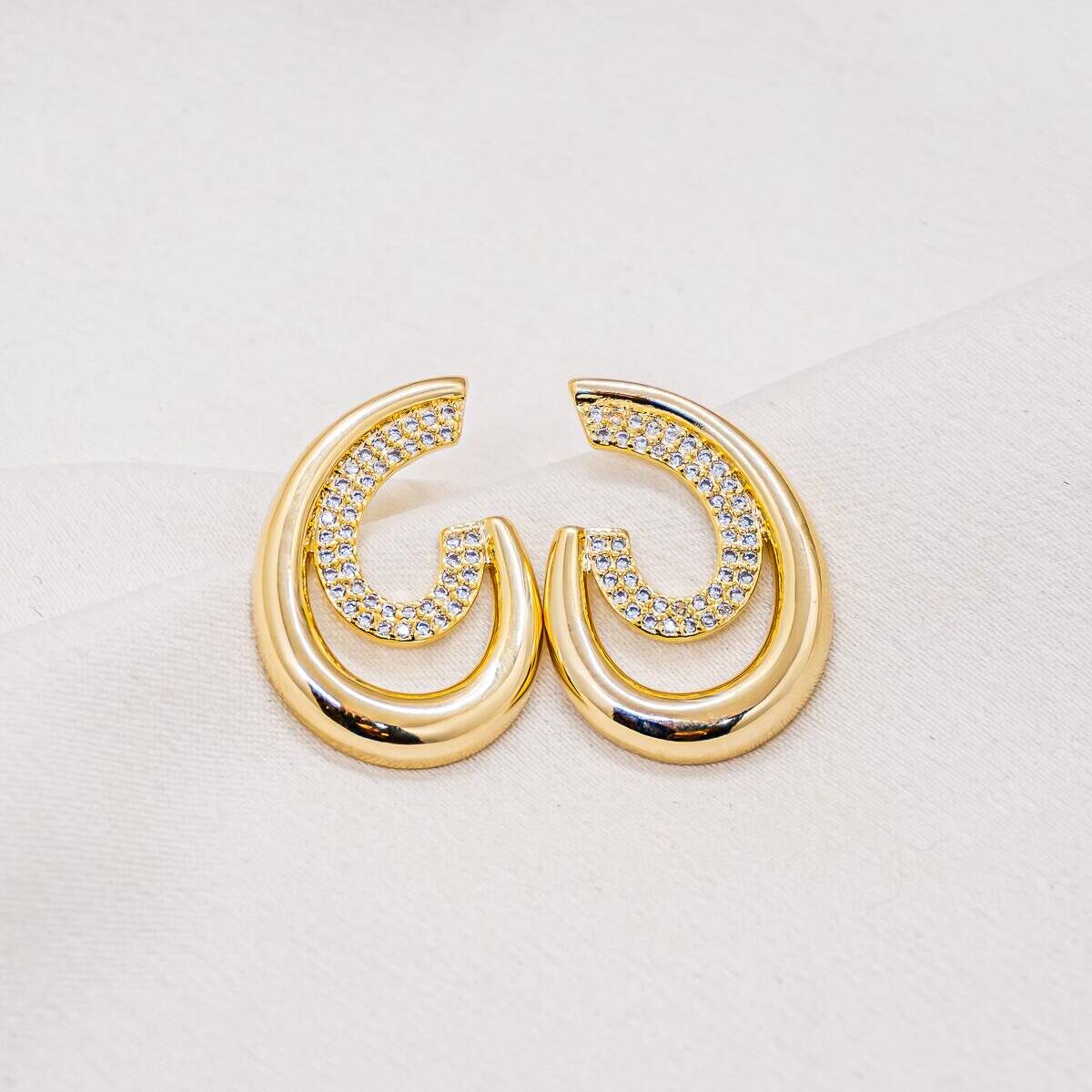 Gold-tone double-hoop earrings, one smooth and one pavé-set with clear stones.