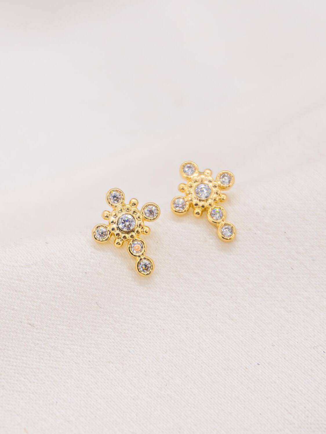 Paire de boucles d’oreilles dorées en petite croix ornée de pierres claires rondes