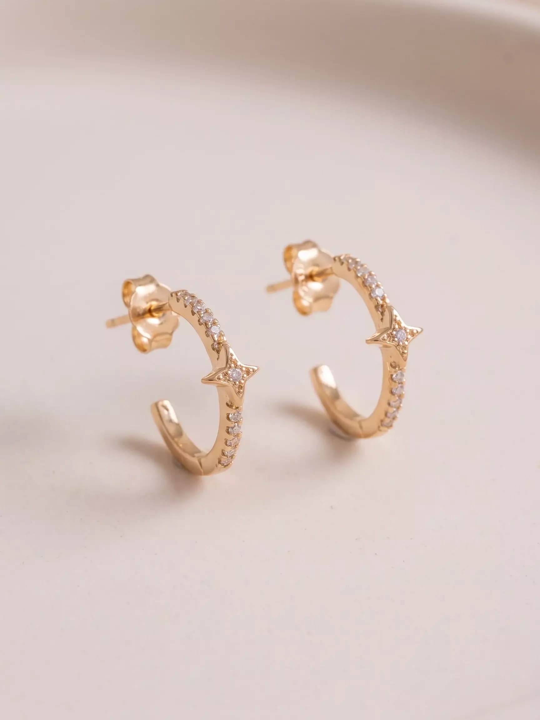 Boucles d'oreilles demi-créole sertie, étoile, la paire posée, vue de près