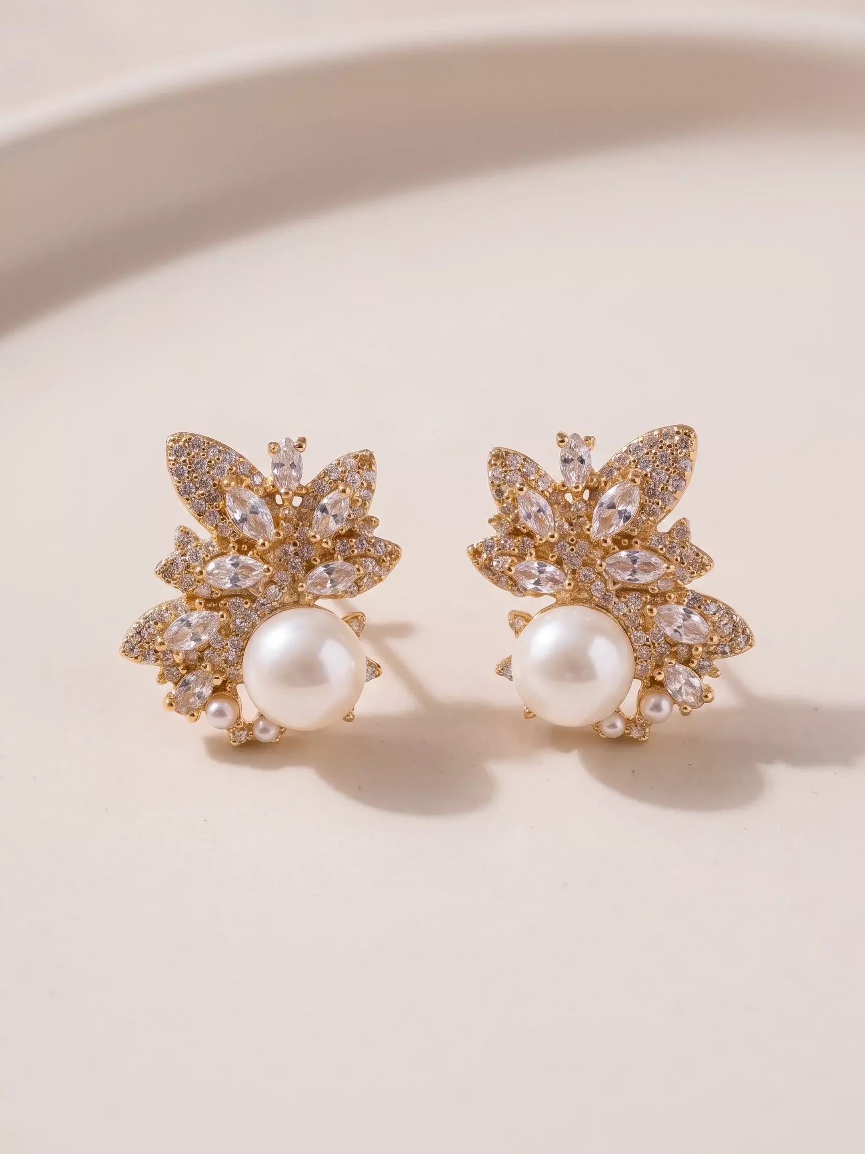 Boucles d'oreilles flore, zircons et perle, la paire posée, vue de près