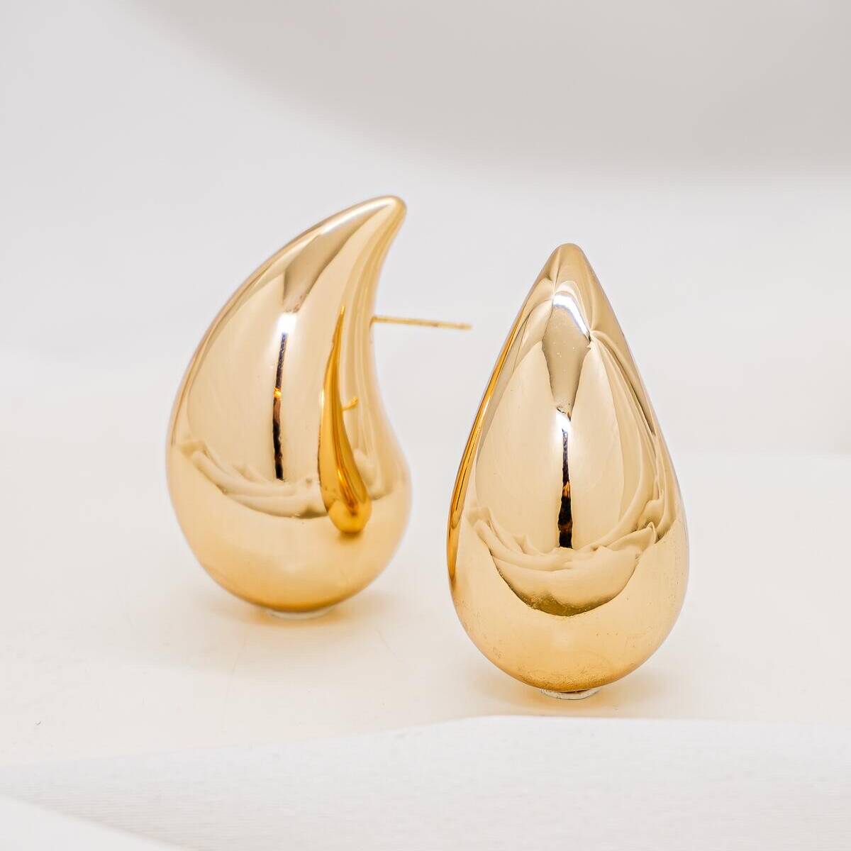 Golden curved teardrop stud earrings with sparkling finish — Display