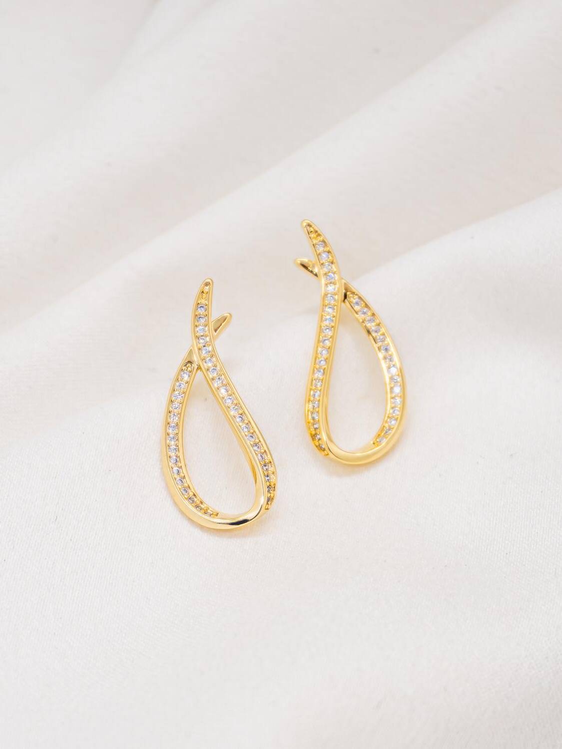 Paire de boucles d’oreilles dorées en goutte ouverte, un bord serti de pierres claires
