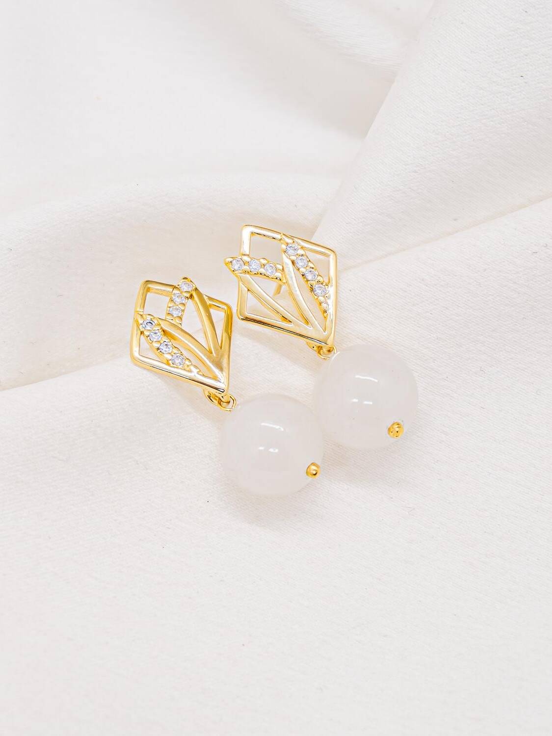 Boucles d’oreilles dorées, losange ajouré serti de pierres claires et grosse bille laiteuse pendante