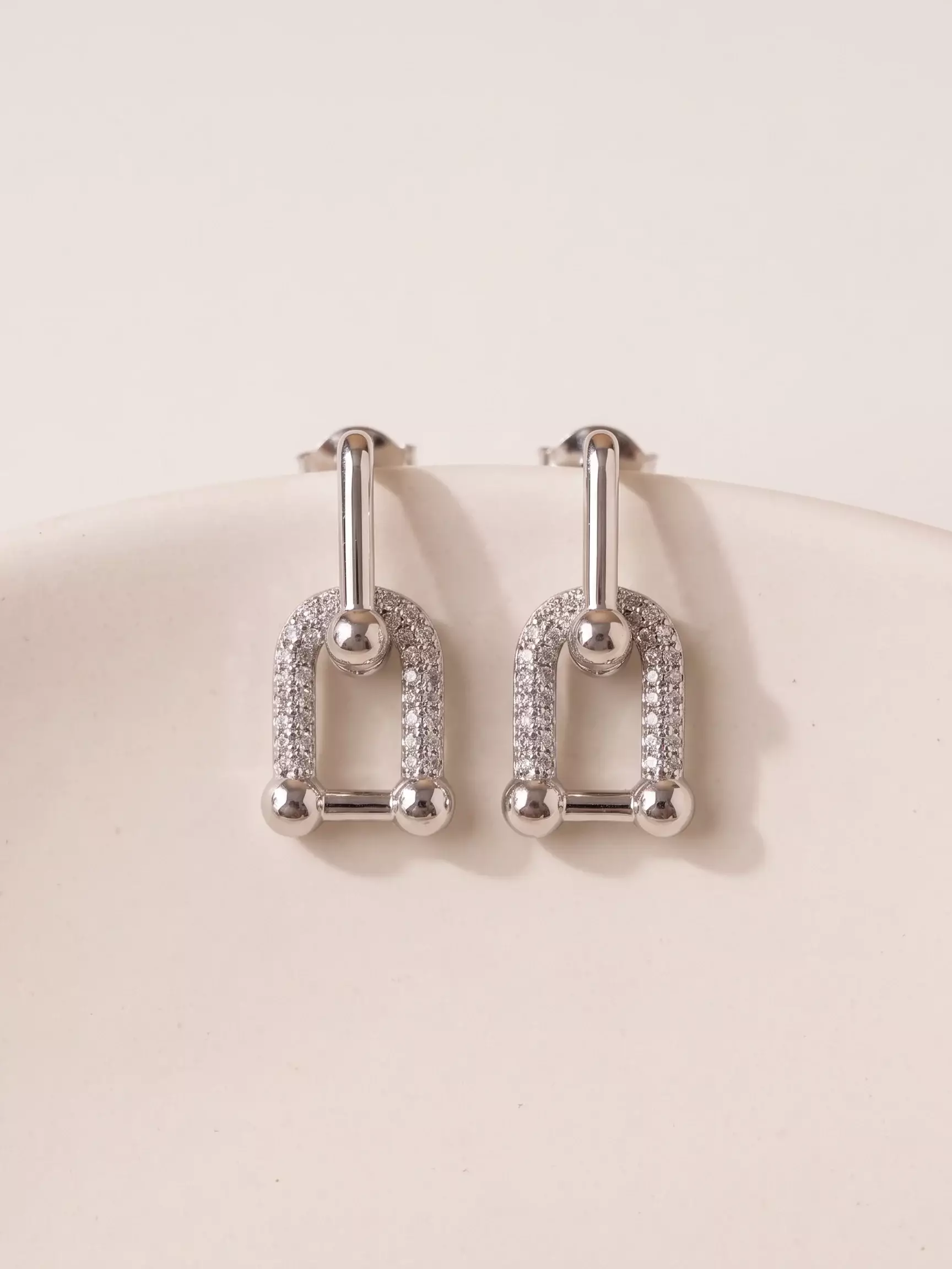 Boucles d'oreilles maillons entrelacés rhodium blanc, la paire posée, vue de près