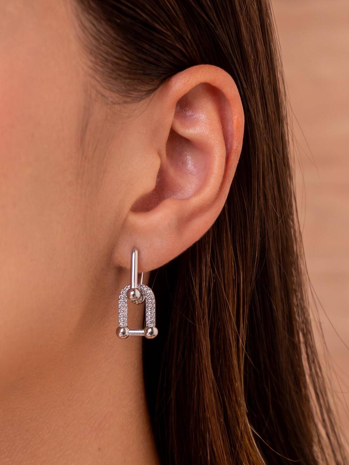 Boucle d’oreille argentée à maillon en U pavé de pierres claires, portée à l’oreille