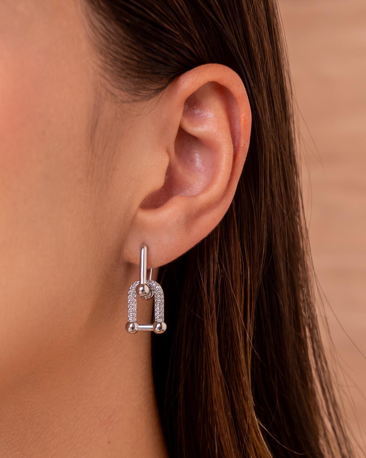 Boucle d’oreille argentée à maillon en U pavé de pierres claires, portée à l’oreille