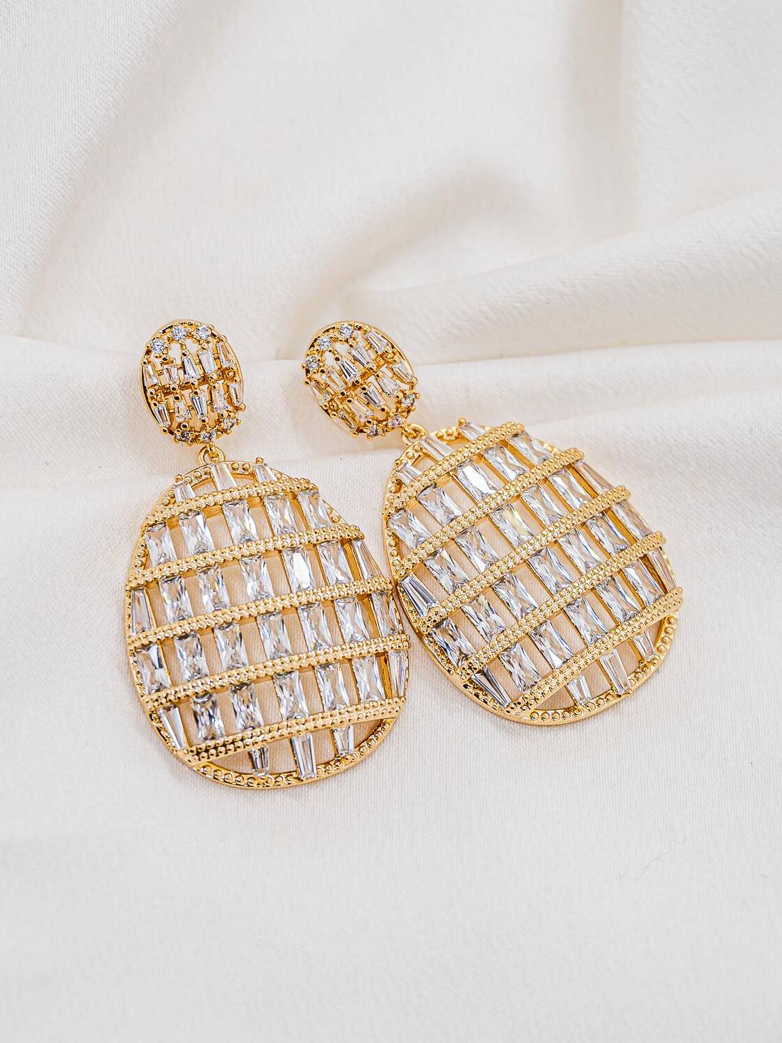 Maxi boucles d’oreilles dorées, grand pendentif ovale ajouré garni de pierres claires en baguette