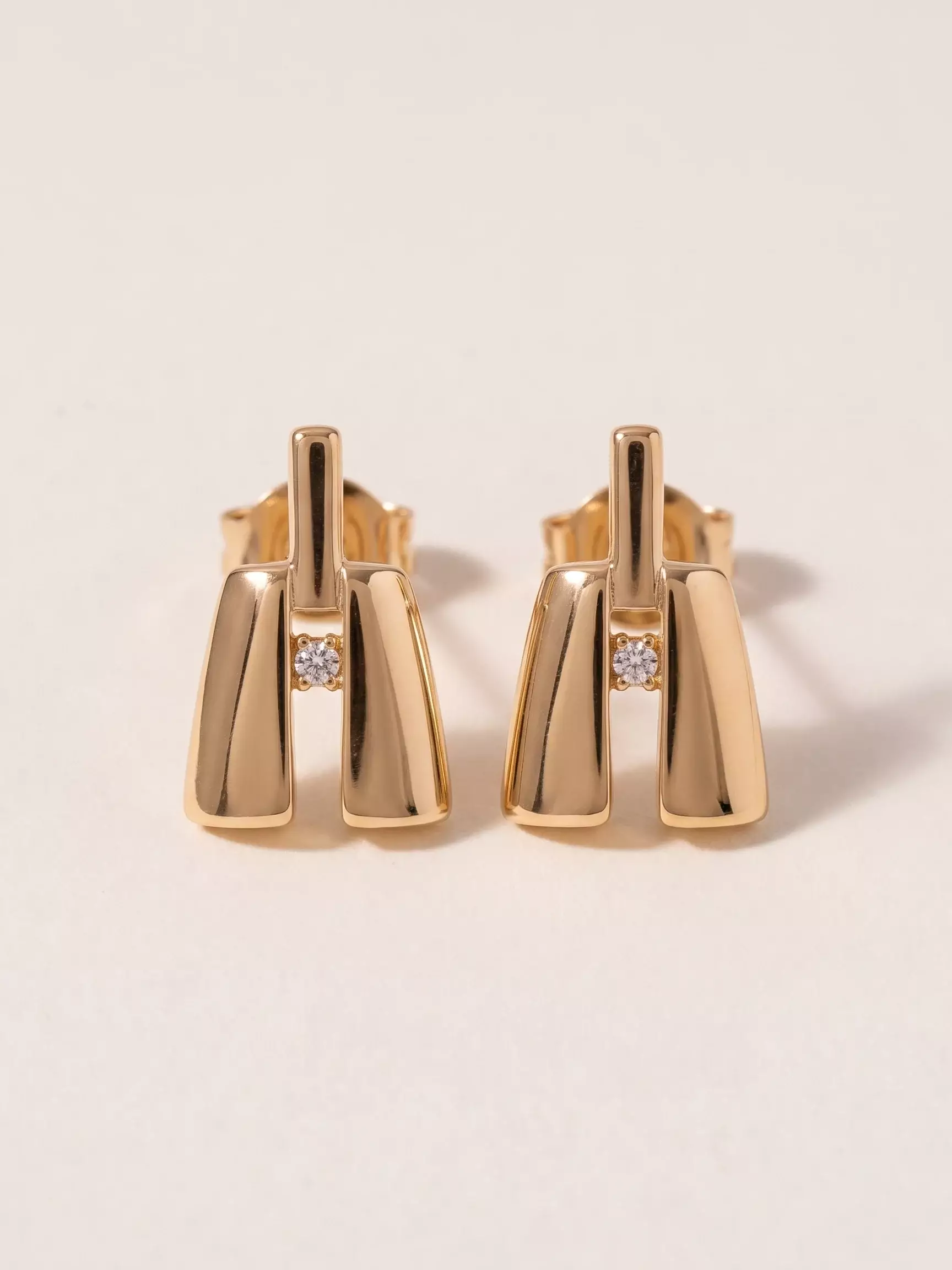 Boucles d'oreilles Notre-Dame stylisée, zircon central, la paire posée, vue de près