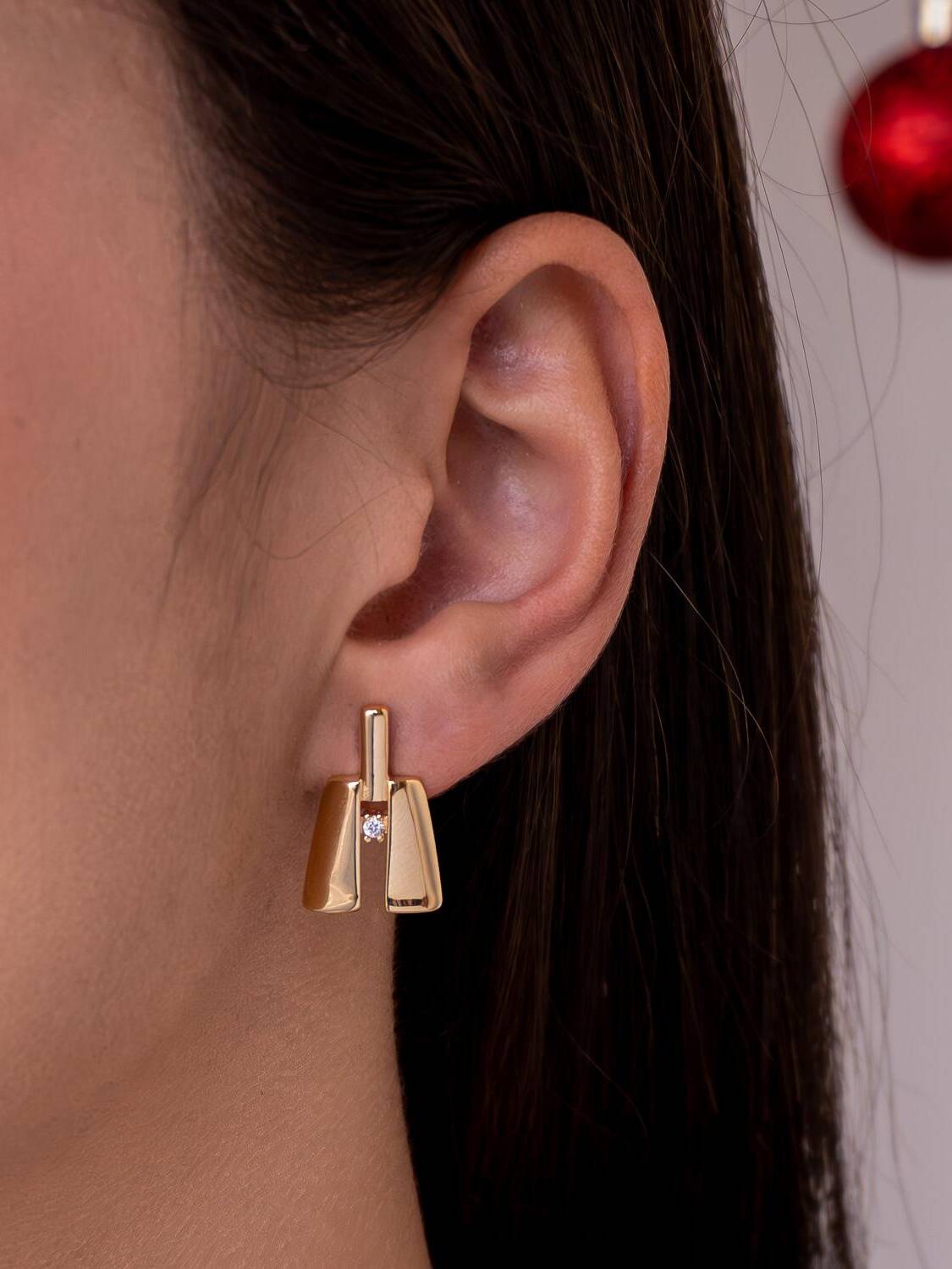 Boucle d’oreille dorée géométrique : deux plaques lisses autour d’une barre avec petit zircon.