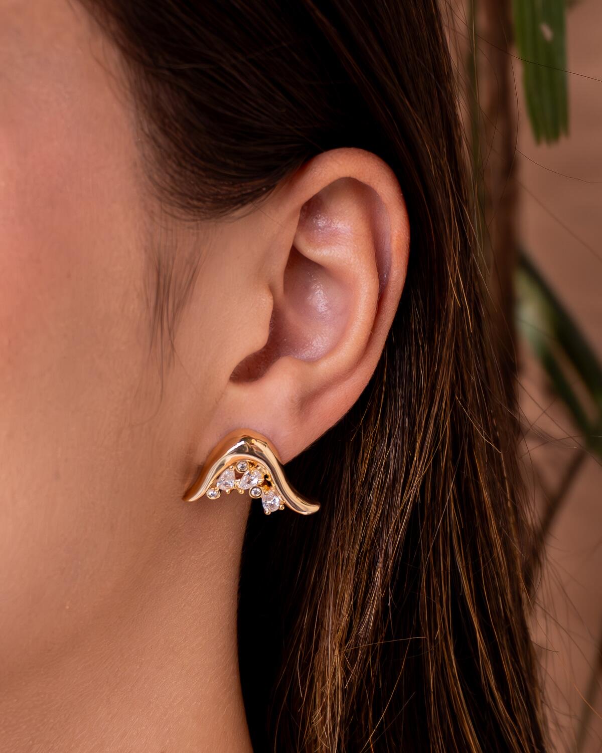 Gold earring with smooth wavy line and small clear stones set in the curve