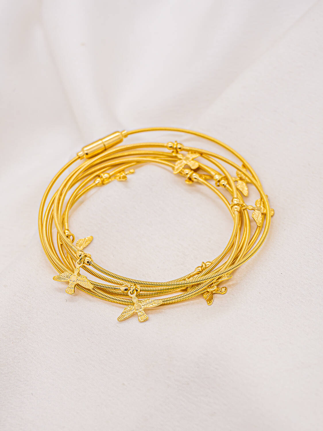 Bracelet doré en plusieurs tours de fils souples ornés de petites colombes