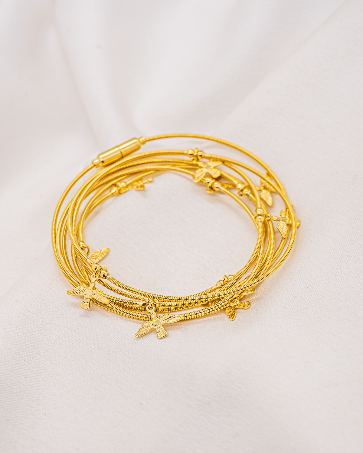 Bracelet doré en plusieurs tours de fils souples ornés de petites colombes