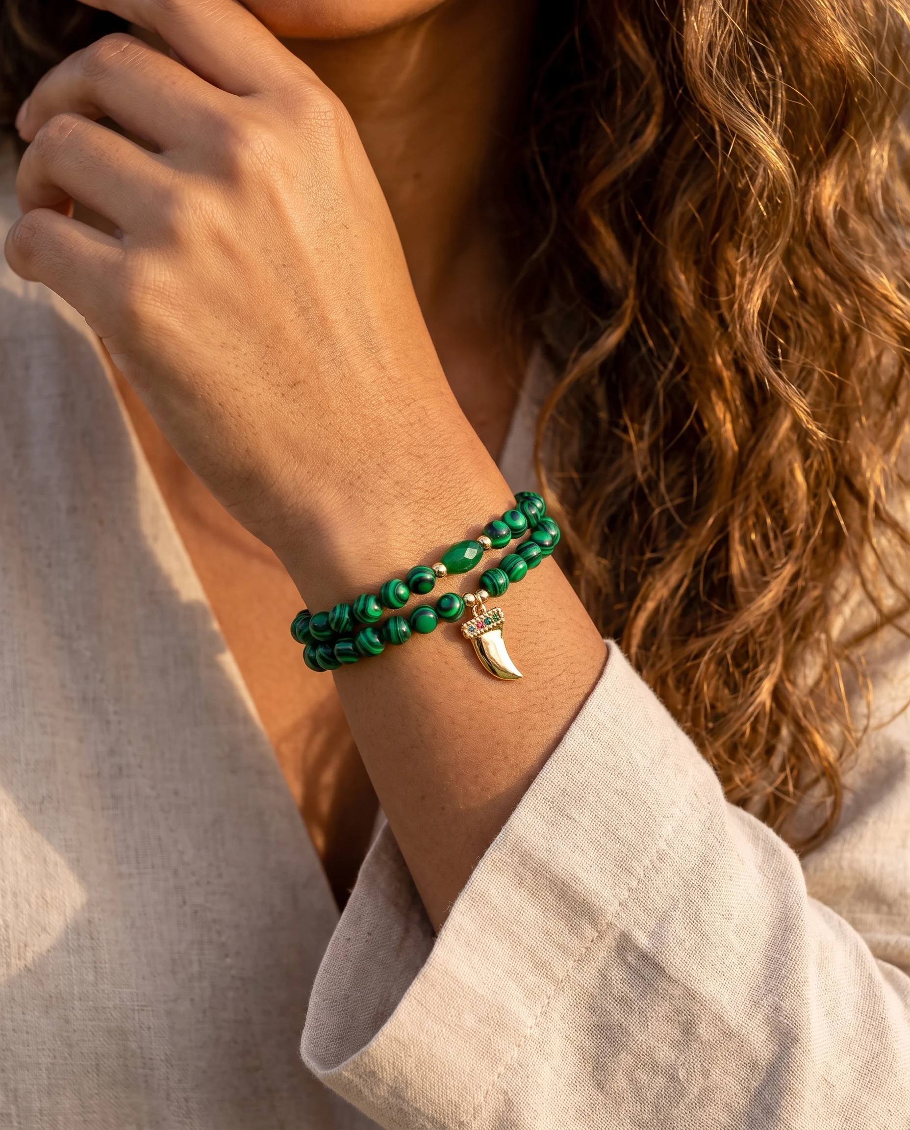 Pulseira dupla de malaquita com pingente de dente e cristal verde, usada no pulso, vista de perto