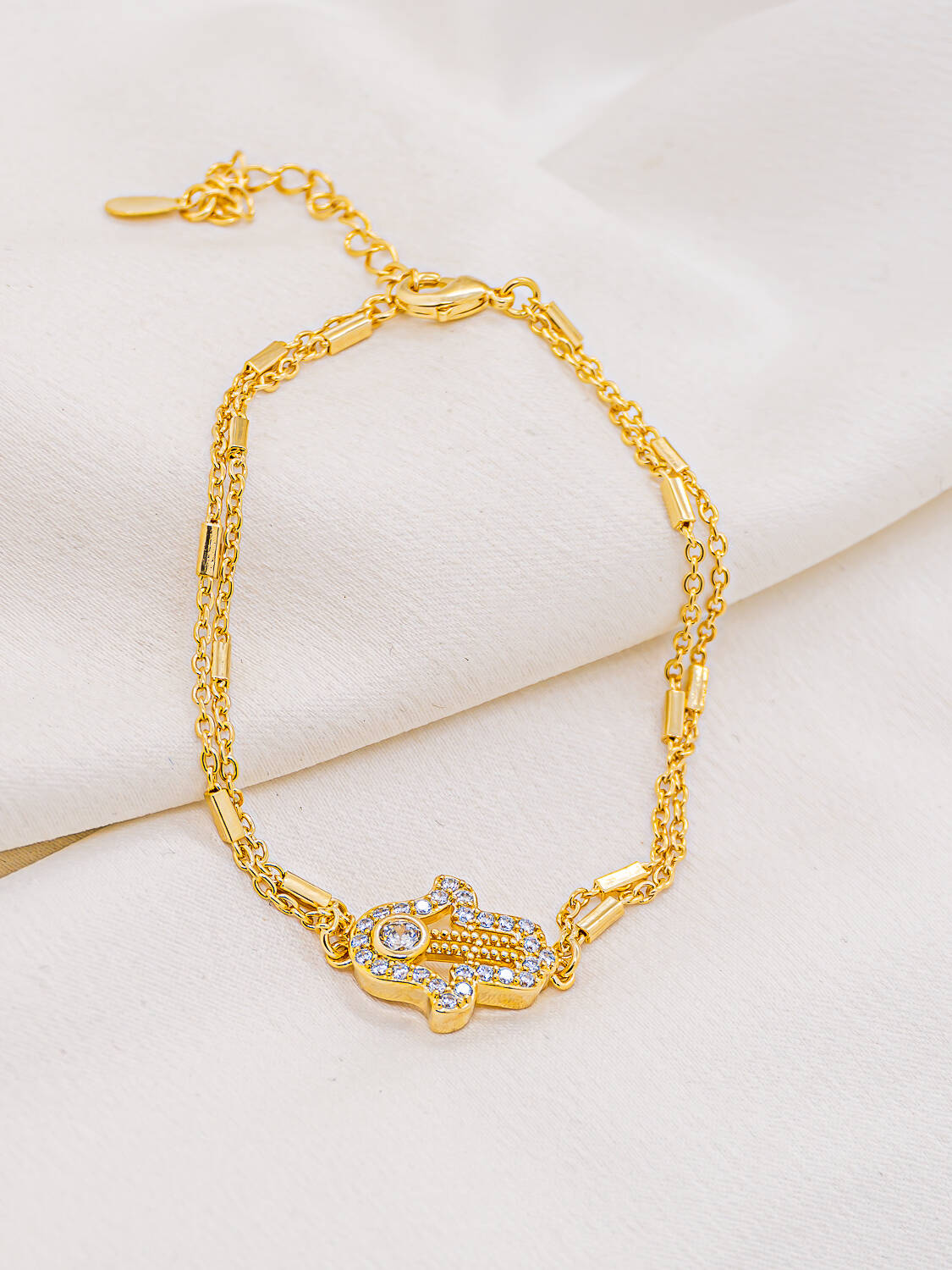 Bracelet doré à double chaîne fine avec main de Fatma sertie de pierres claires