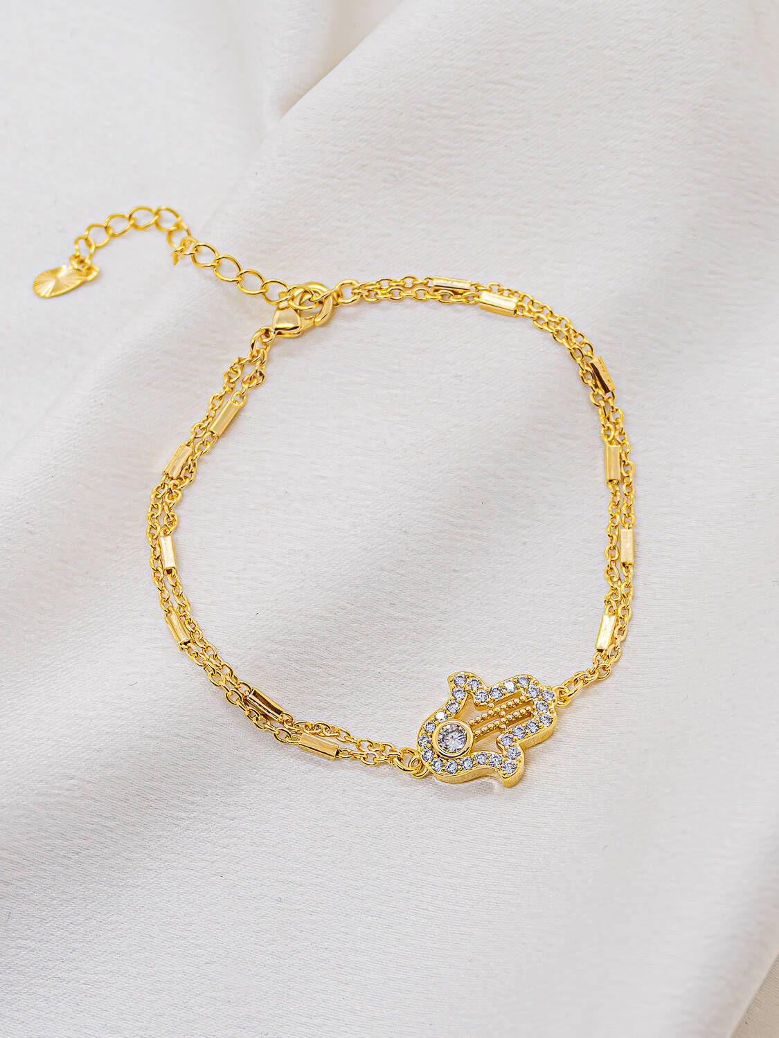 Bracelet doré à deux chaînes fines avec main de Fatma bordée de petites pierres claires