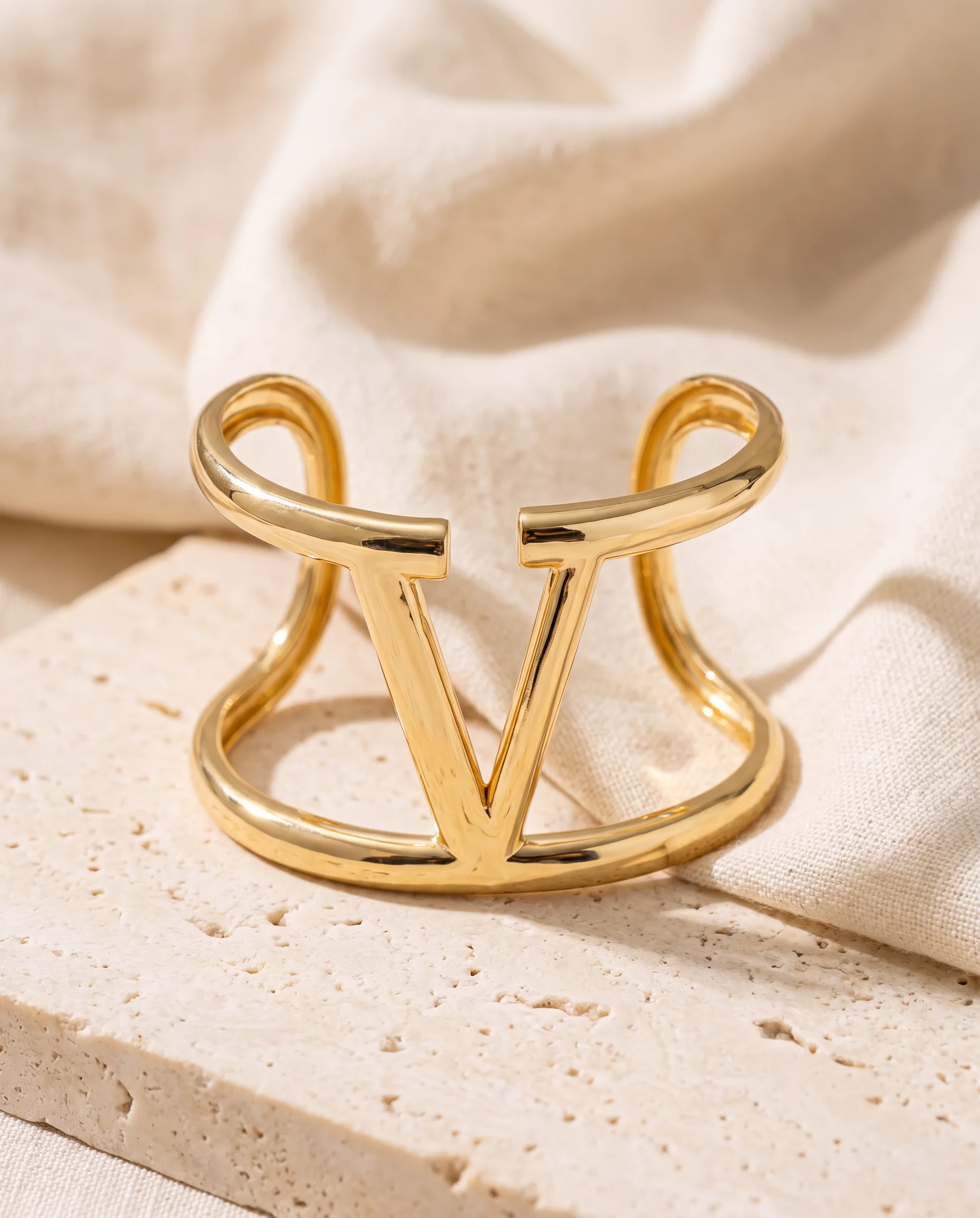Gold V openwork cuff standing on a light stone
