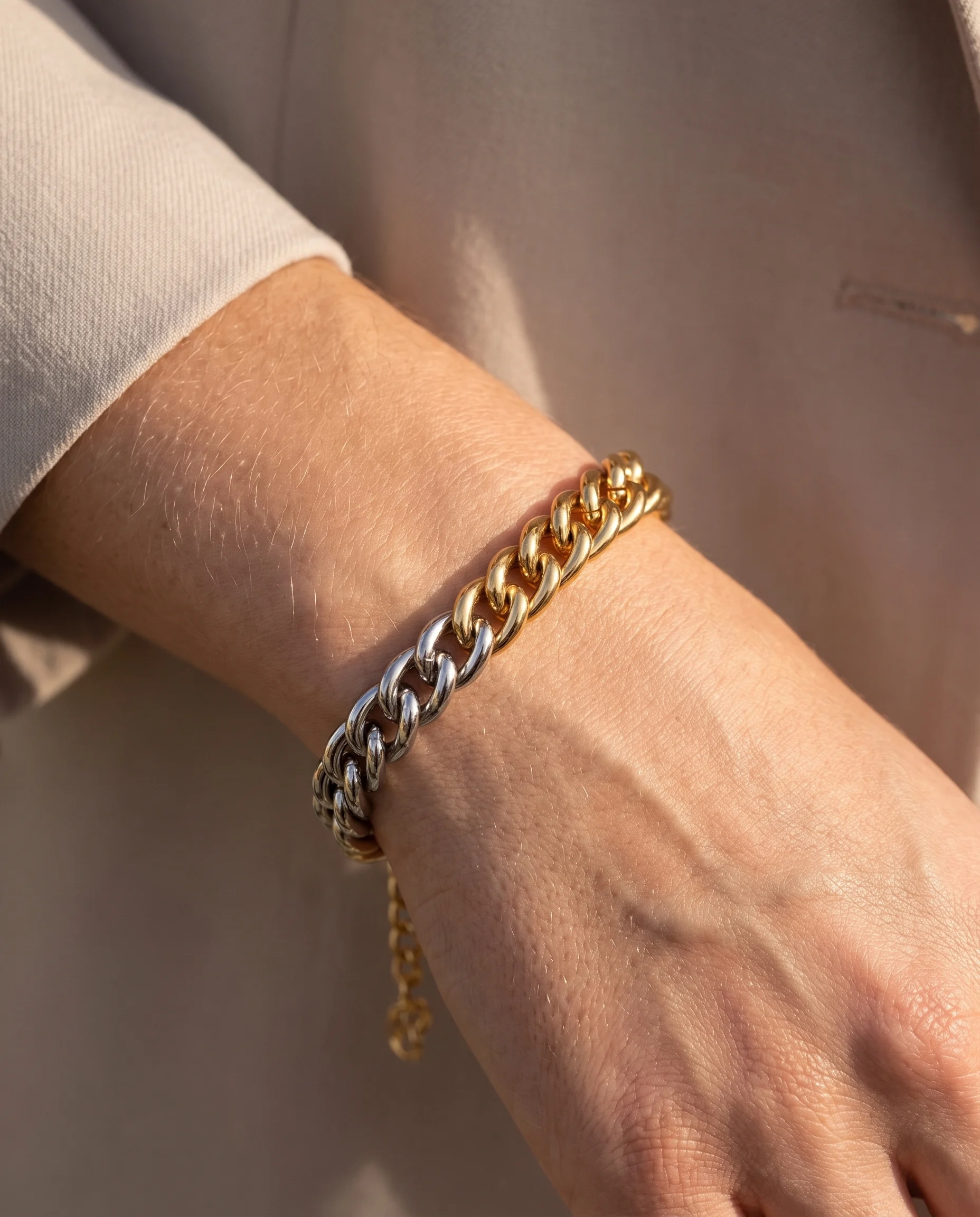 Maxi curb chain bracelet in gold and white rhodium, worn on the wrist, close-up