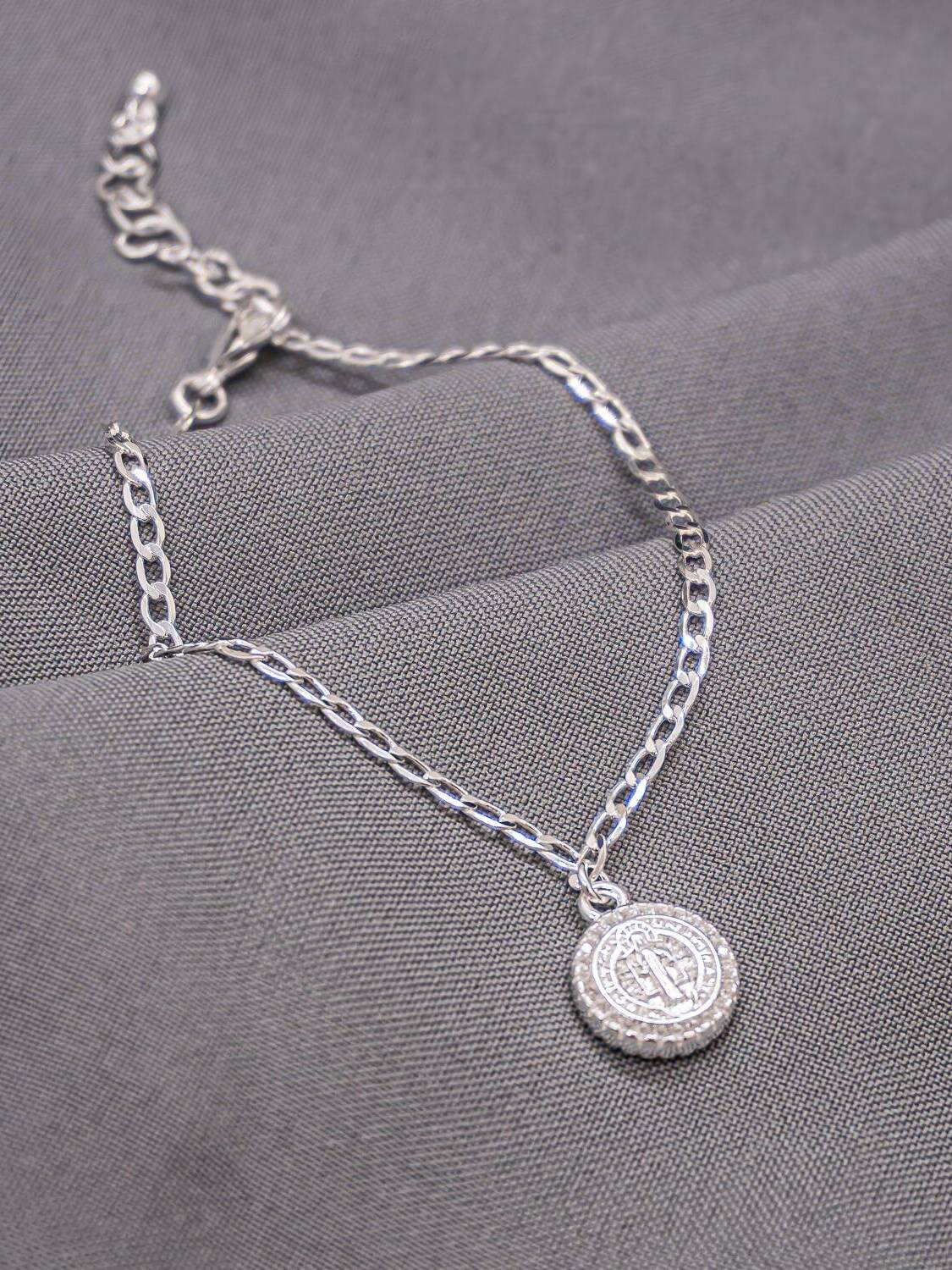 Bracelet argenté en fine chaîne gourmette, petite médaille Saint Benoît bordée de pierres claires