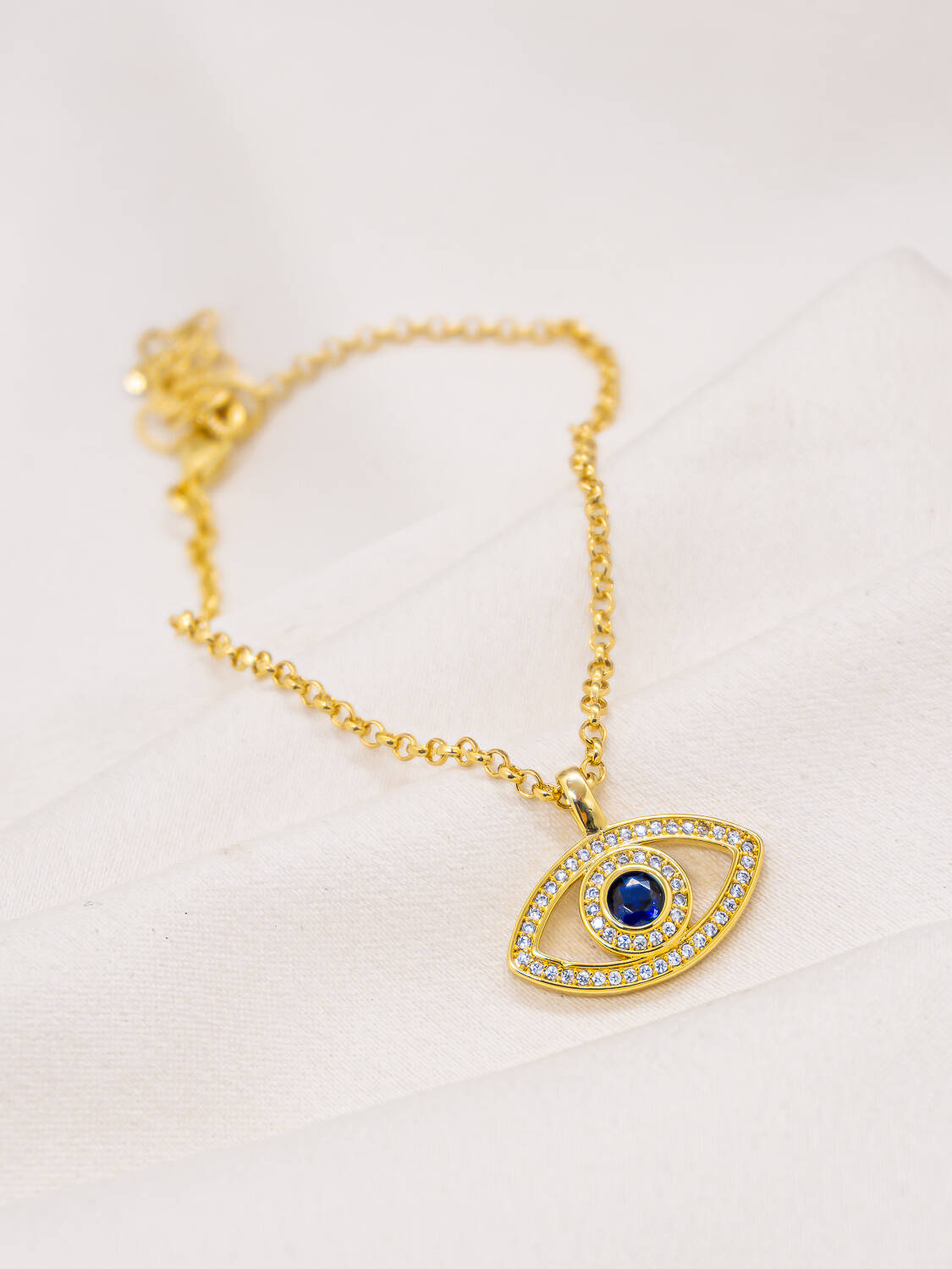 Bracelet doré à fine chaîne avec pendentif œil grec ajouré, pierre centrale bleue et pierres claires
