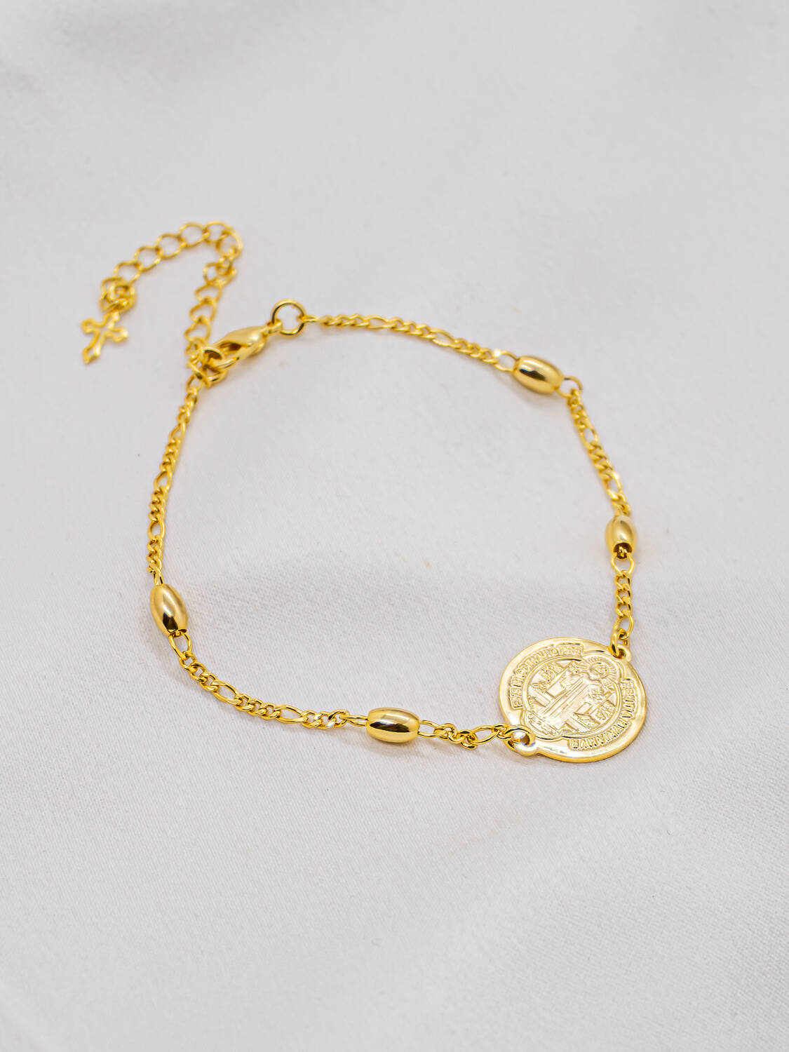 Bracelet doré à petites olives de métal, médaille ronde de Saint Benoît et petite croix