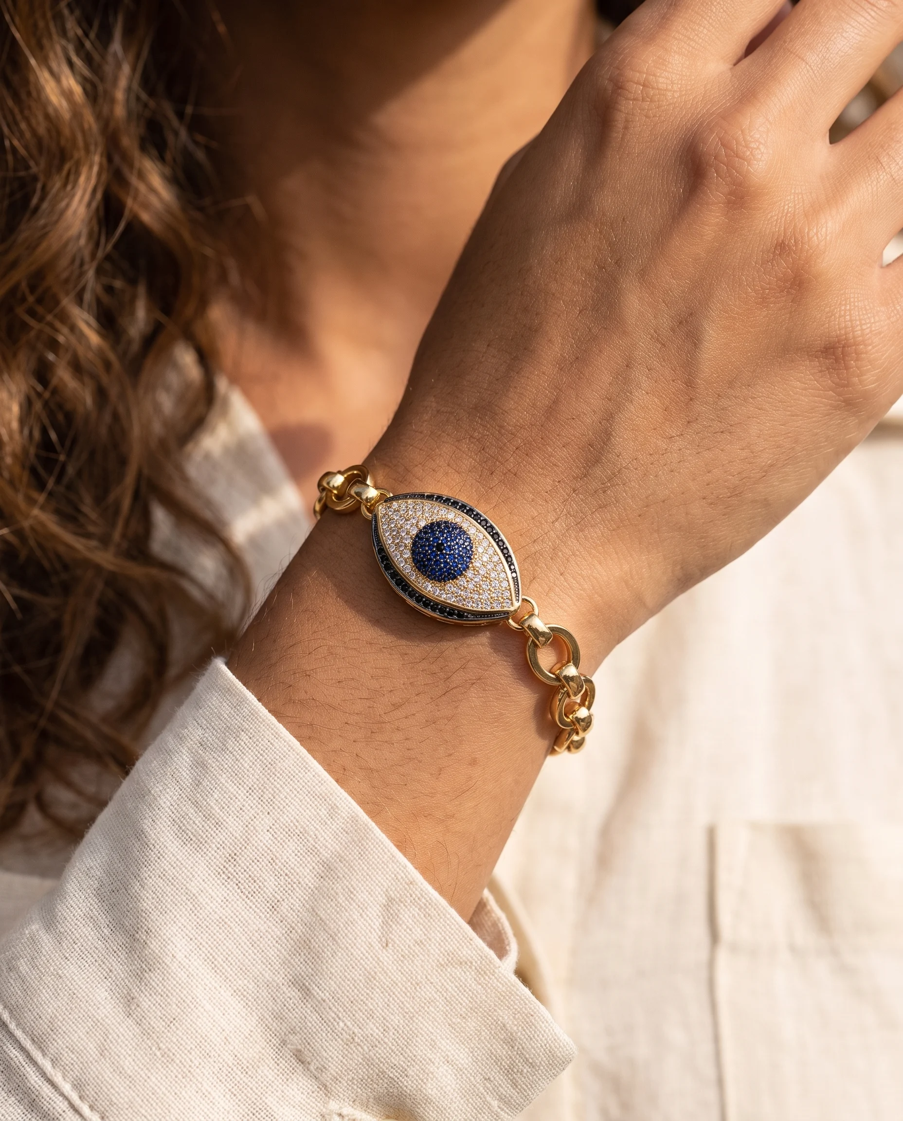 Pulseira de elos maxi, olho grego cravejado azul, usada no pulso, vista de perto