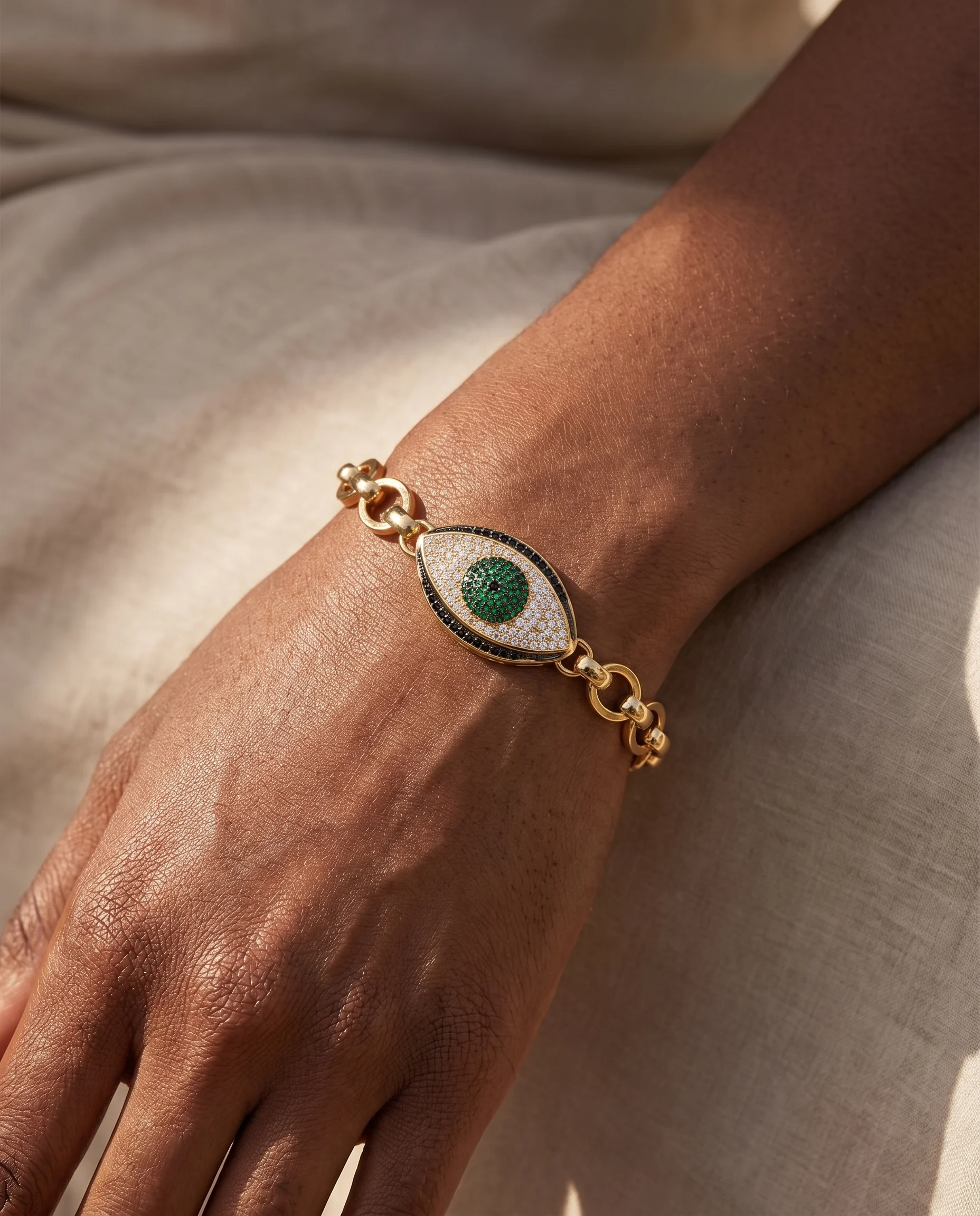 Maxi-link bracelet, pavé-set green Greek eye, worn on wrist, close-up view
