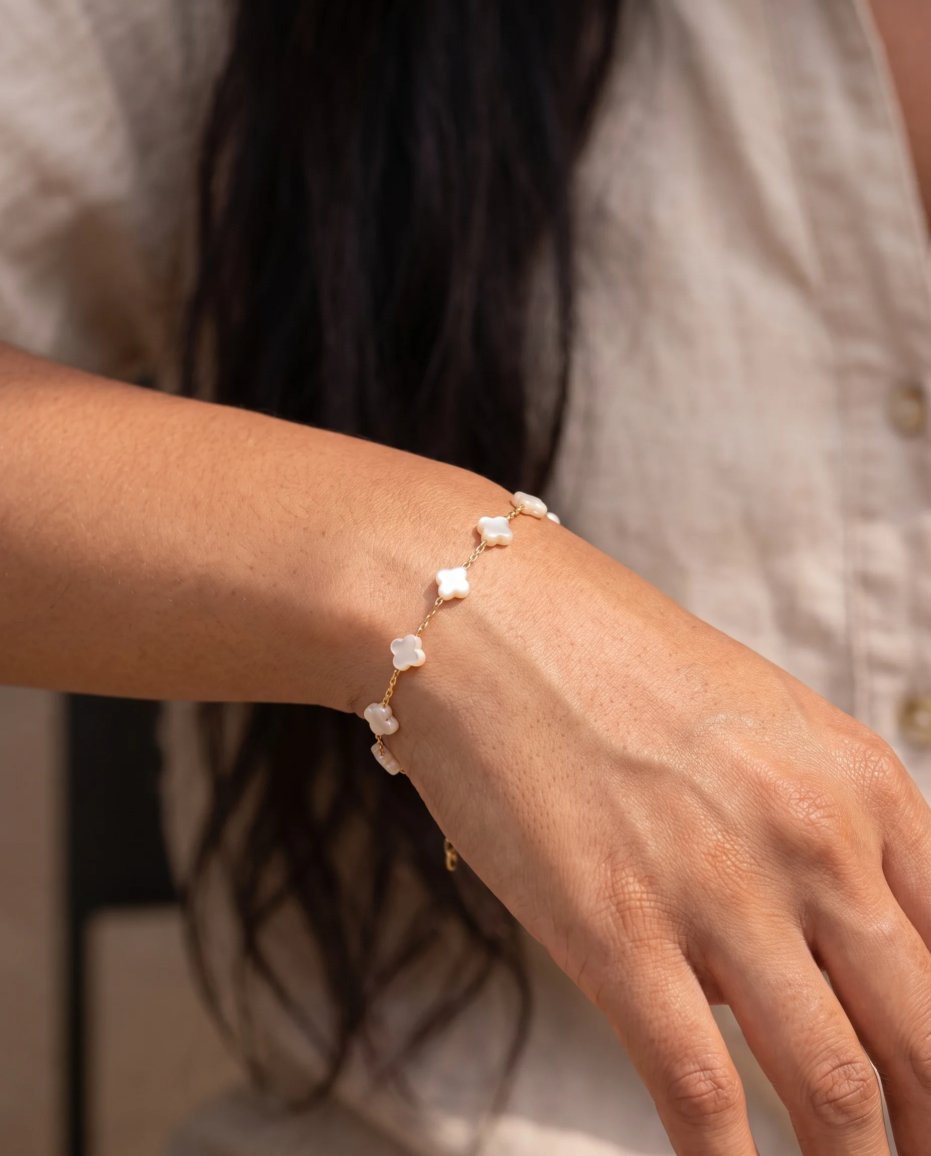 Bracelet mini maillons, trèfles nacre, porté au poignet, vu de près