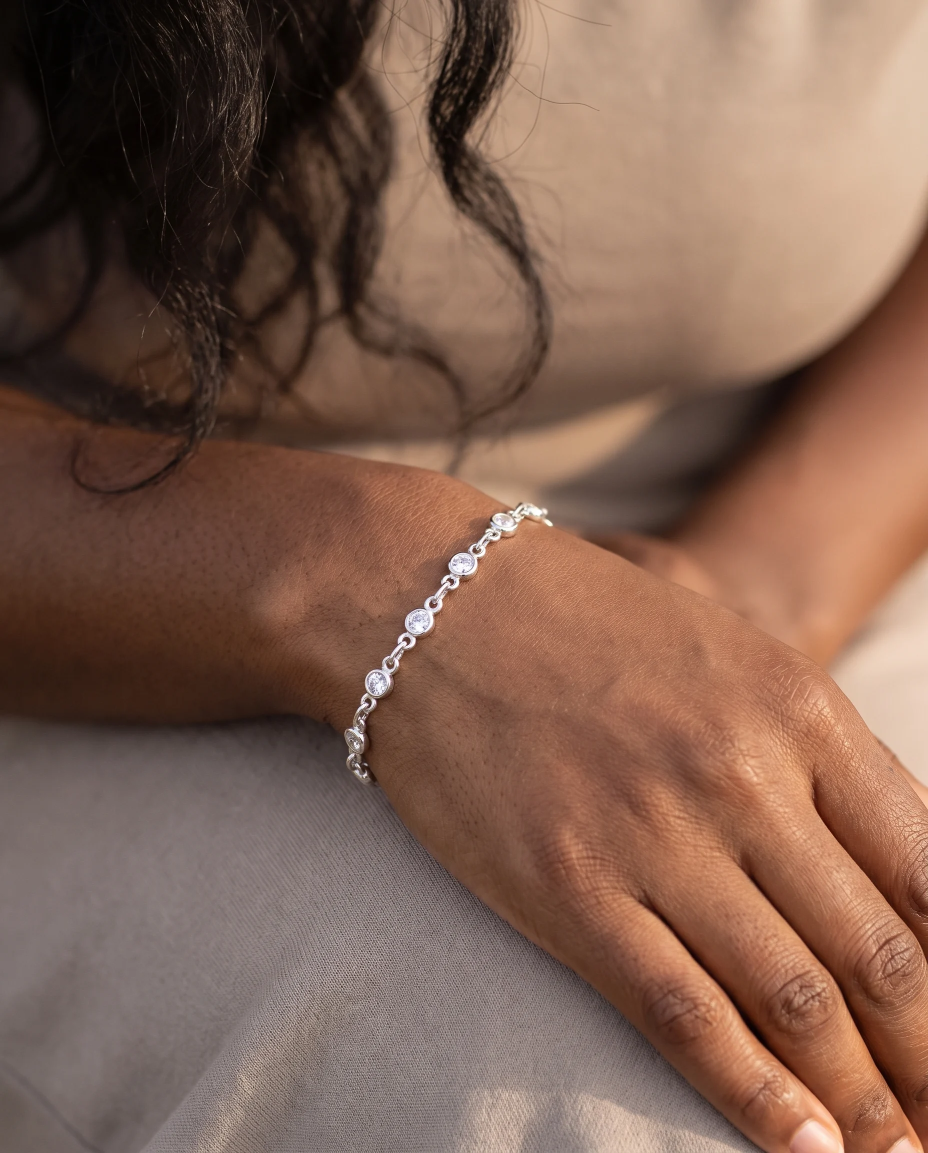 Bracelet mini maillons, zircons ronds, finition argentée, porté au poignet, vu de près