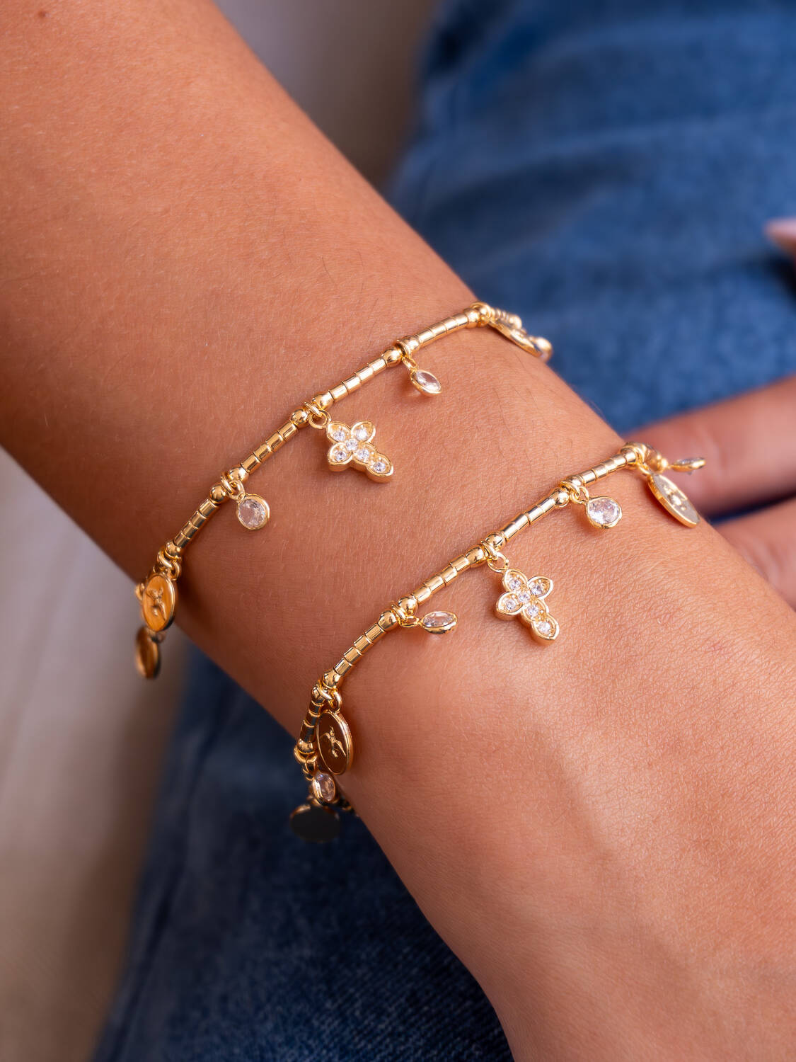 Deux bracelets dorés à perles tubes, petites croix serties de pierres claires et médailles, portés