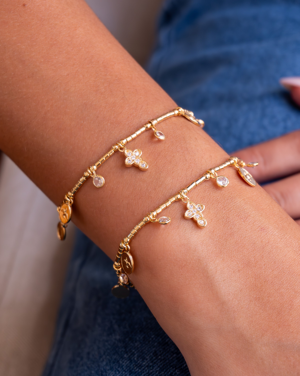 Deux bracelets dorés à perles tubes, petites croix serties de pierres claires et médailles, portés