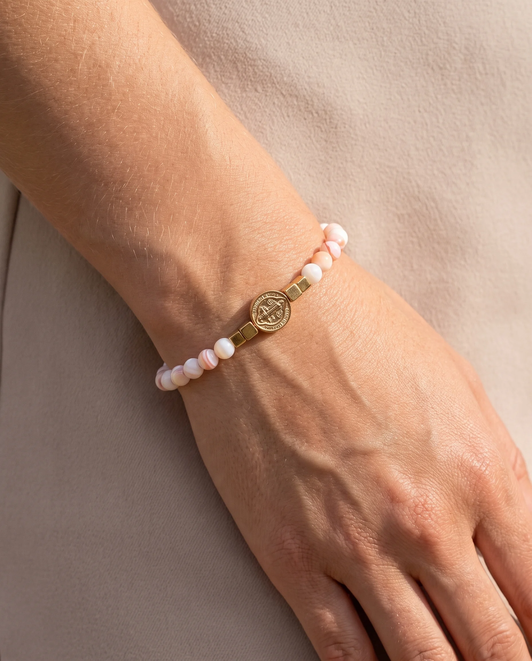 Bracelet nacre colorée petite médaille Saint Benoît, porté au poignet, vu de près