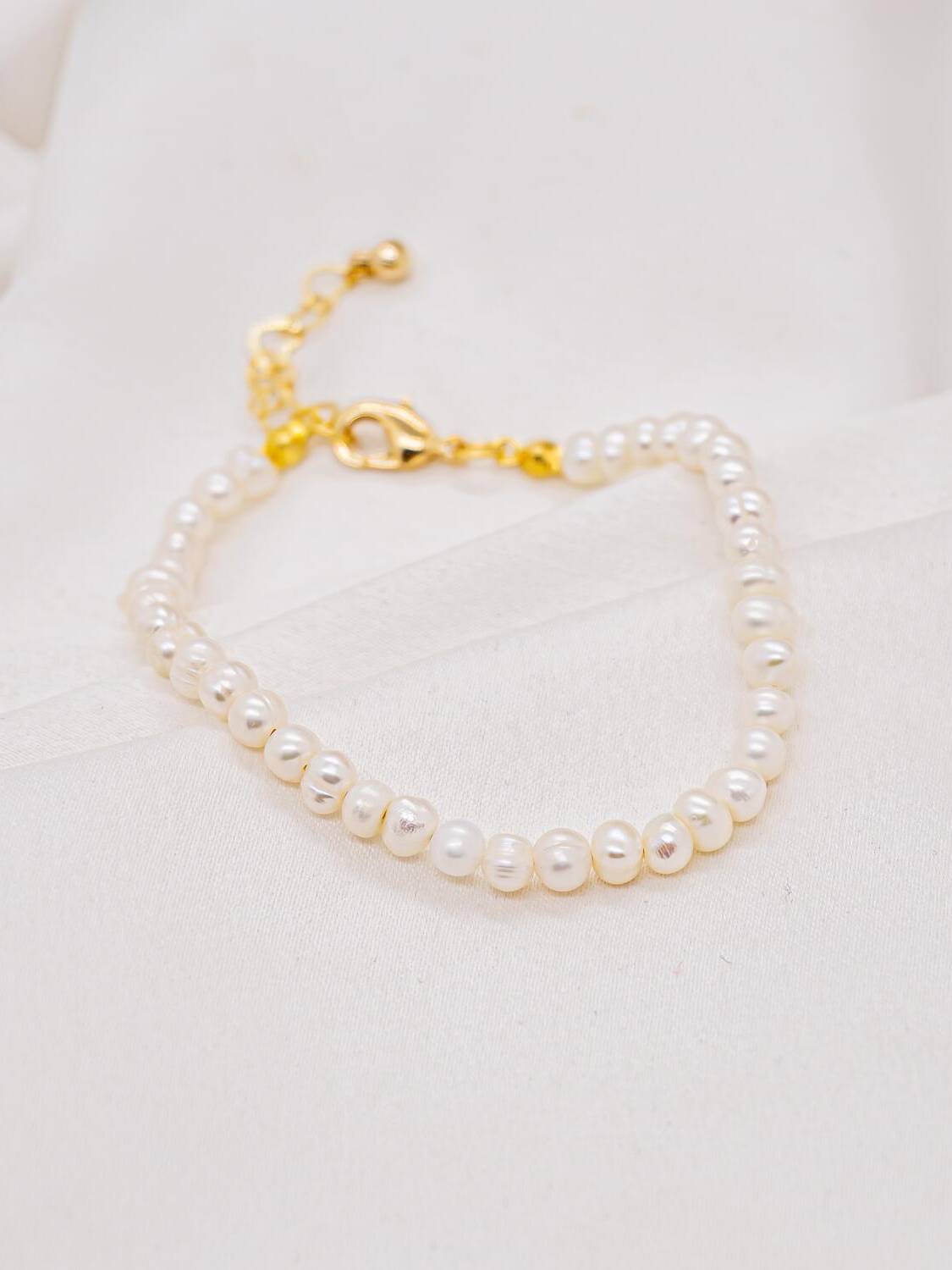 Bracelet de petites perles blanches nacrées avec fermoir mousqueton doré et chaînette