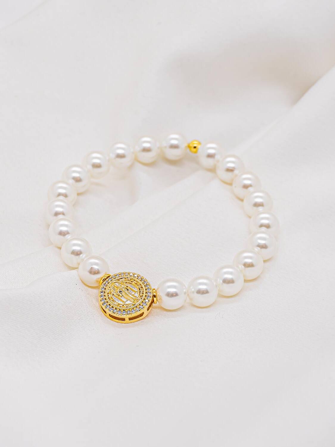 Bracelet de perles blanches rondes avec médaille dorée ajourée bordée de pierres claires