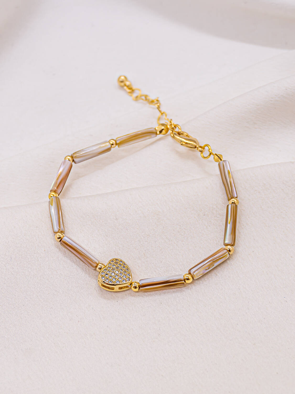 Bracelet de perles tubes en nacre et boules dorées, cœur serti