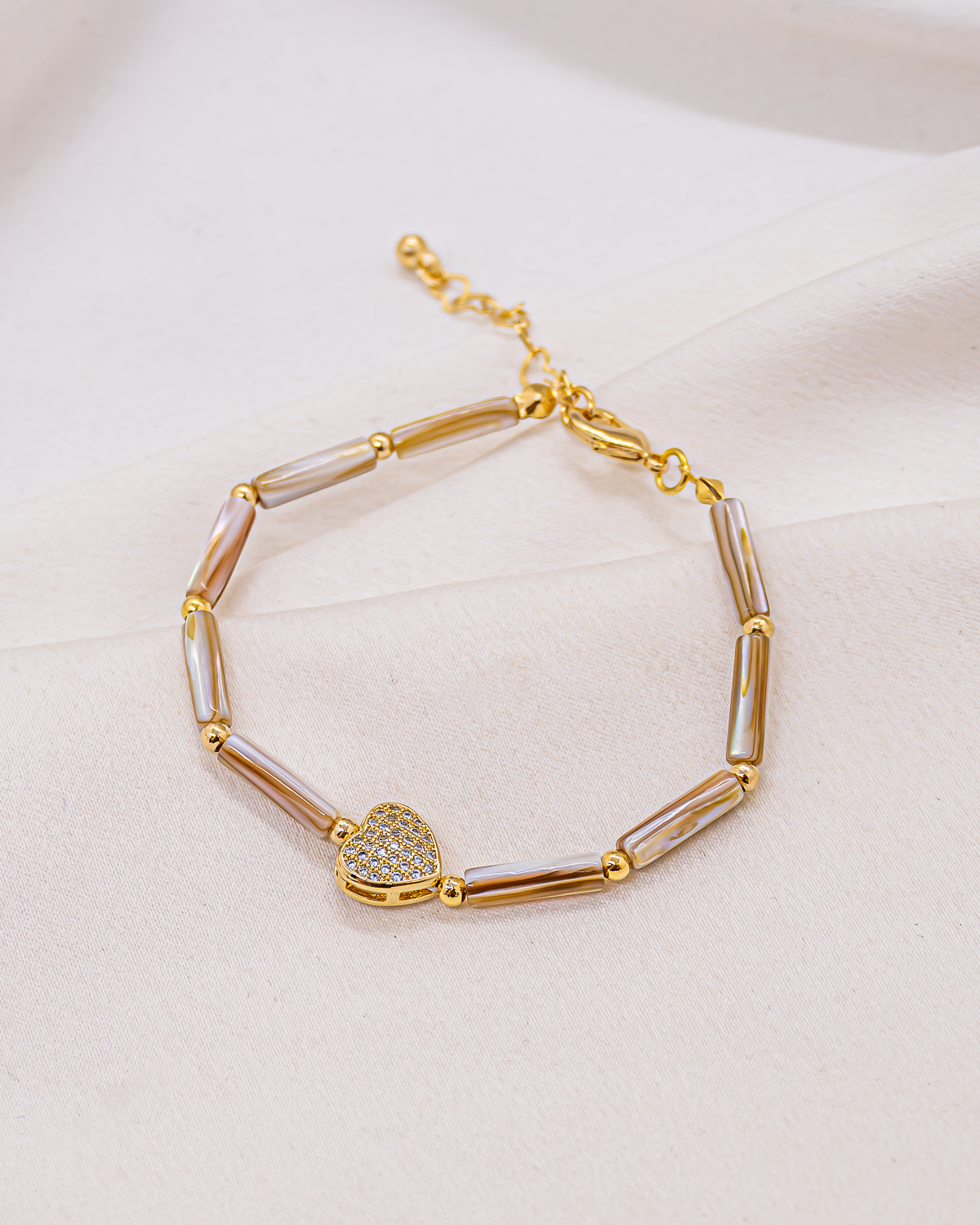 Bracelet de perles tubes en nacre et boules dorées, cœur serti