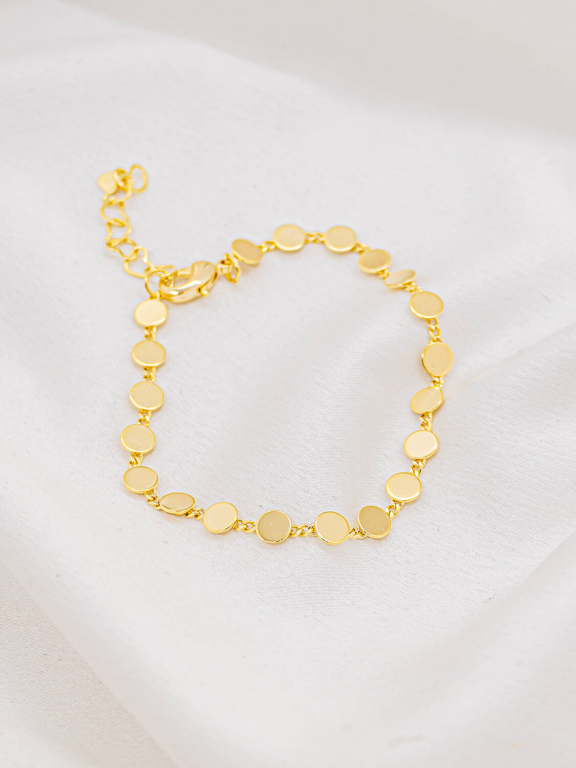 Bracelet doré de petites plaques rondes et lisses reliées par de fins maillons