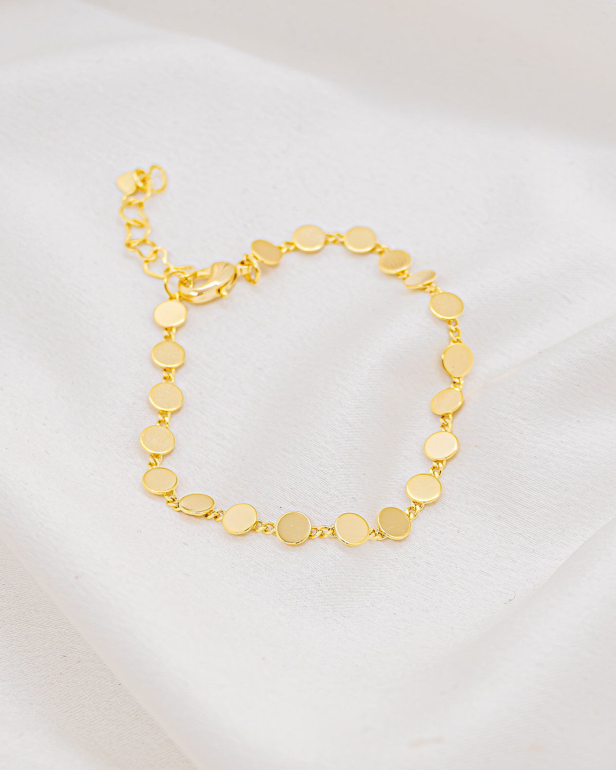 Pulseira dourada de pequenas placas redondas e lisas conectadas por elos finos