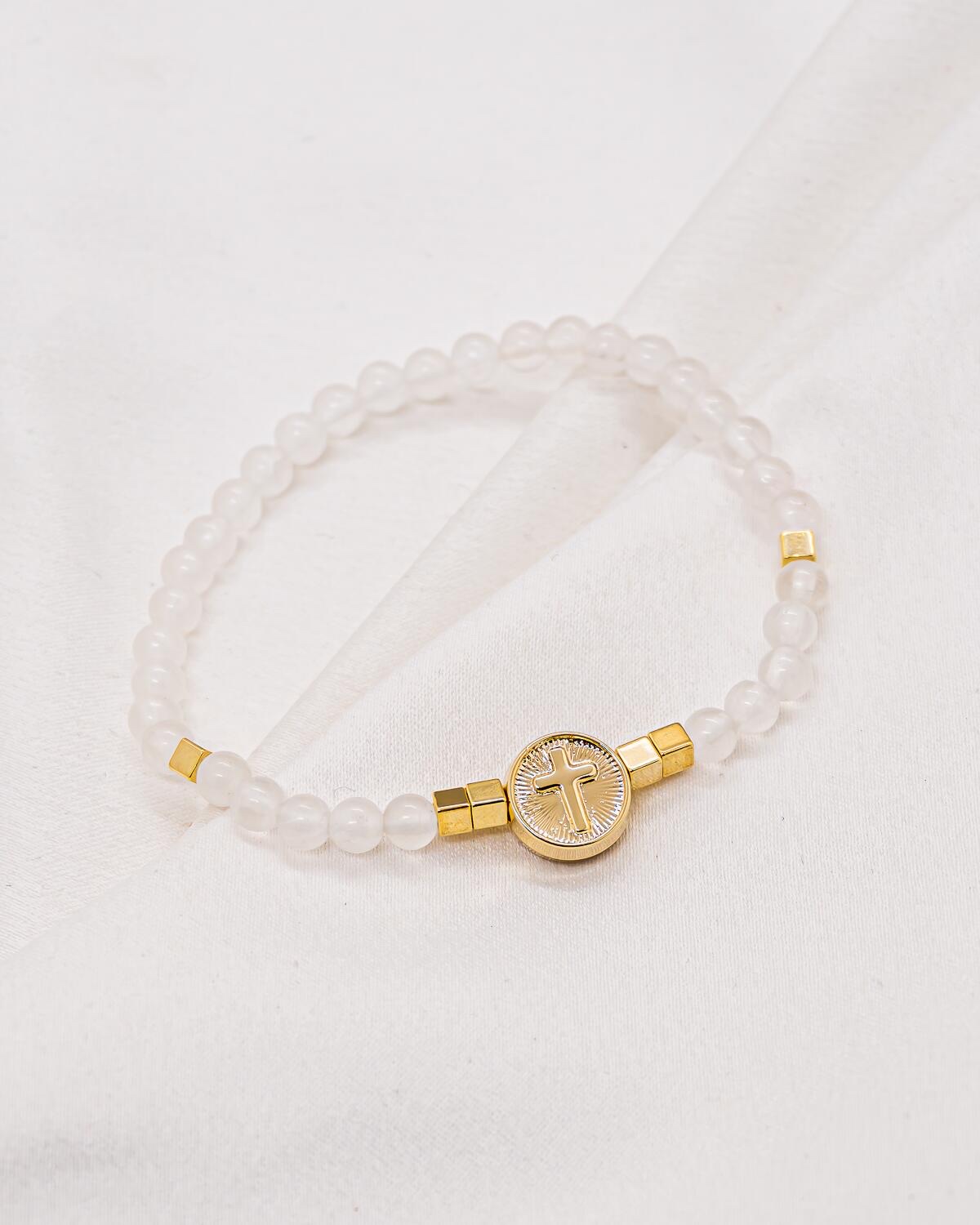 Bracelet de billes blanches translucides avec médaille ronde dorée ornée d’une croix
