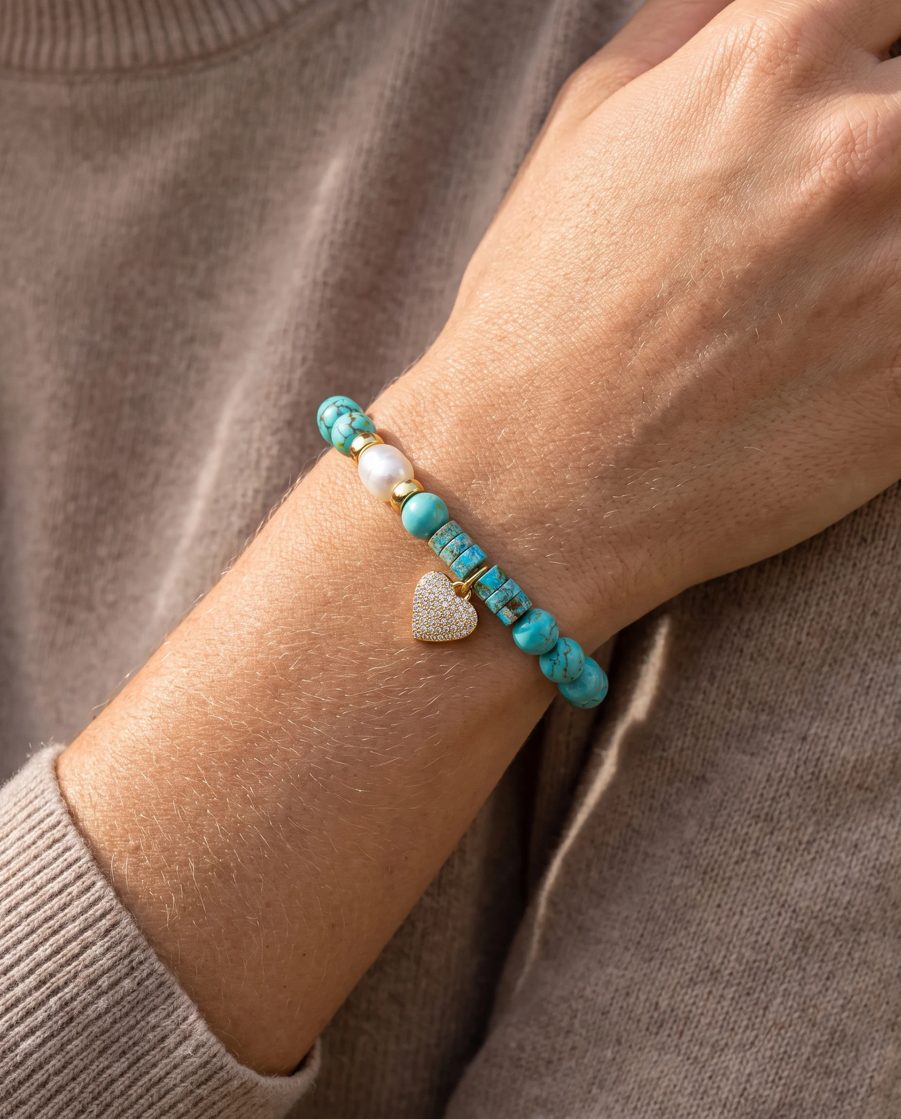 Turquoise natural stone bead bracelet with pearl and pavé-set heart, worn on the wrist, close-up