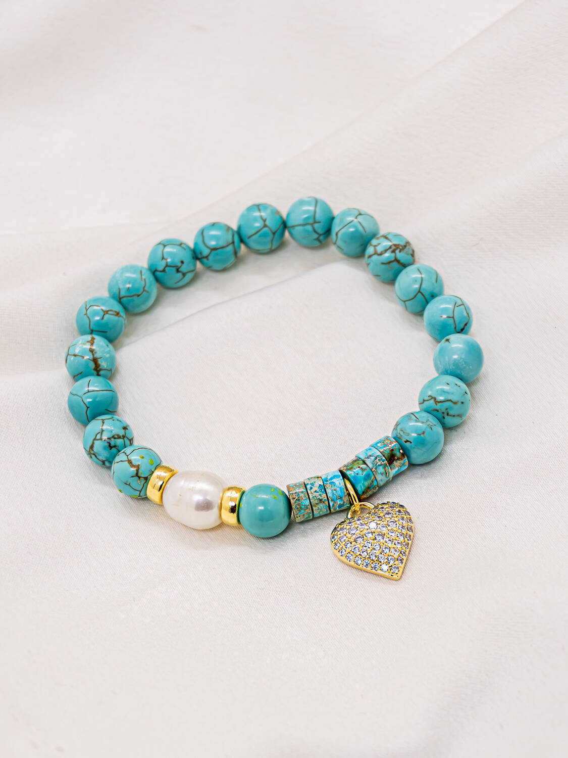 Bracelet de perles turquoise veinées, une perle blanche et un cœur doré serti