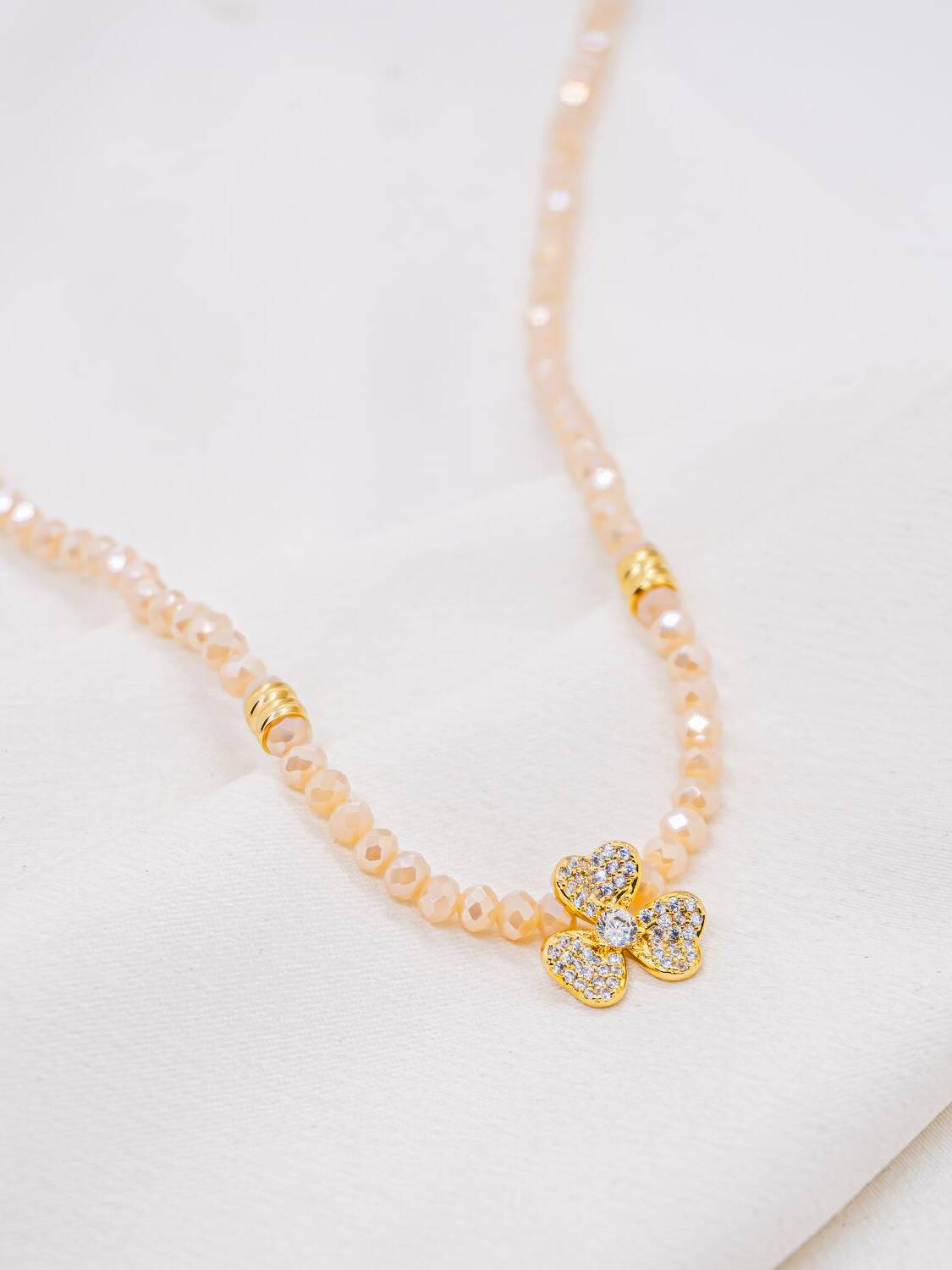 Collier de cristaux facettés rose pâle, fleur à trois pétales sertie de pierres claires au centre