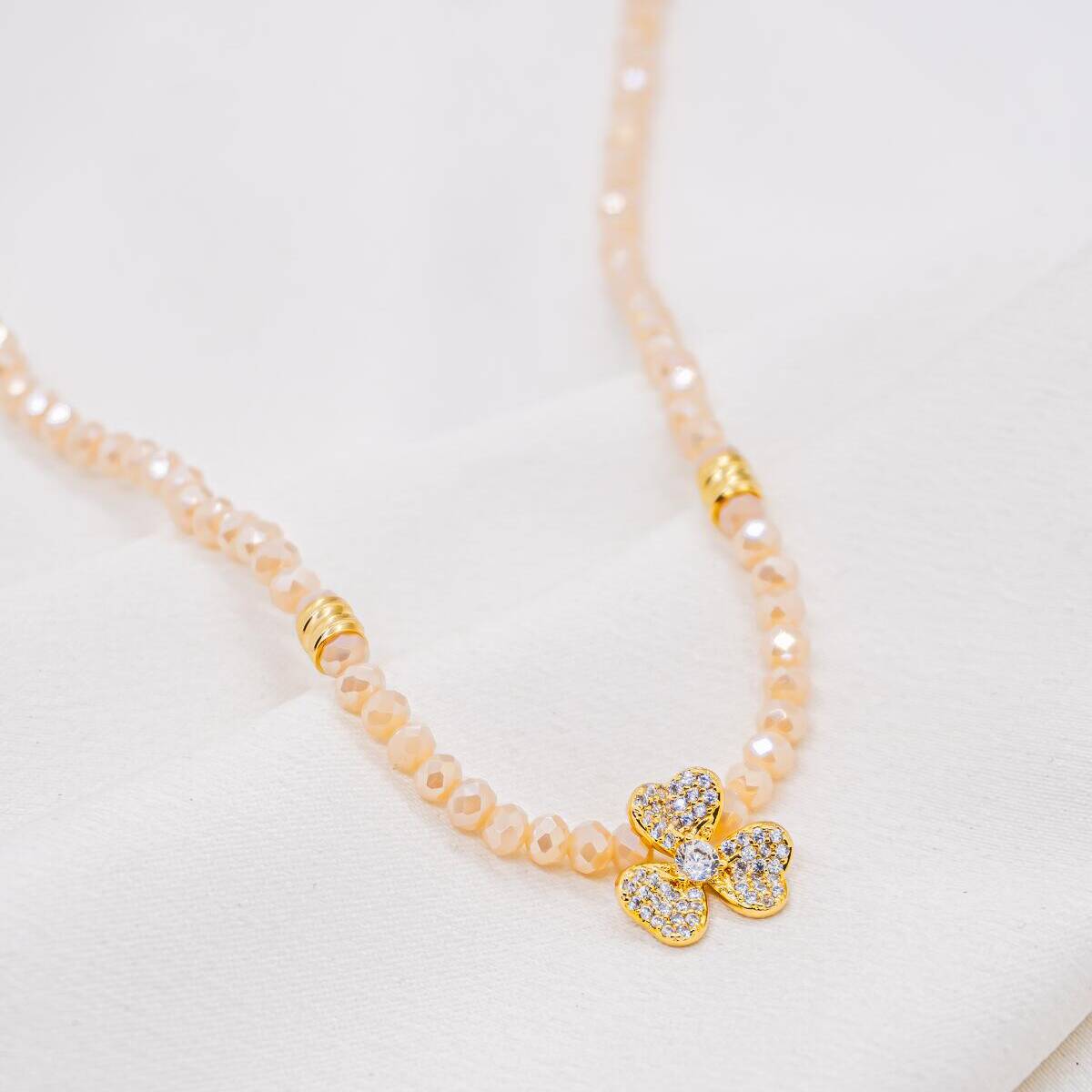 Pale pink faceted crystal necklace with a clear stone-set three-petal flower at the center